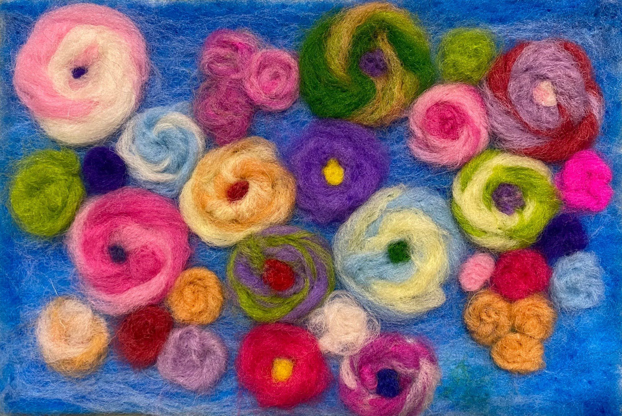 A felt painting of many colourful flowers