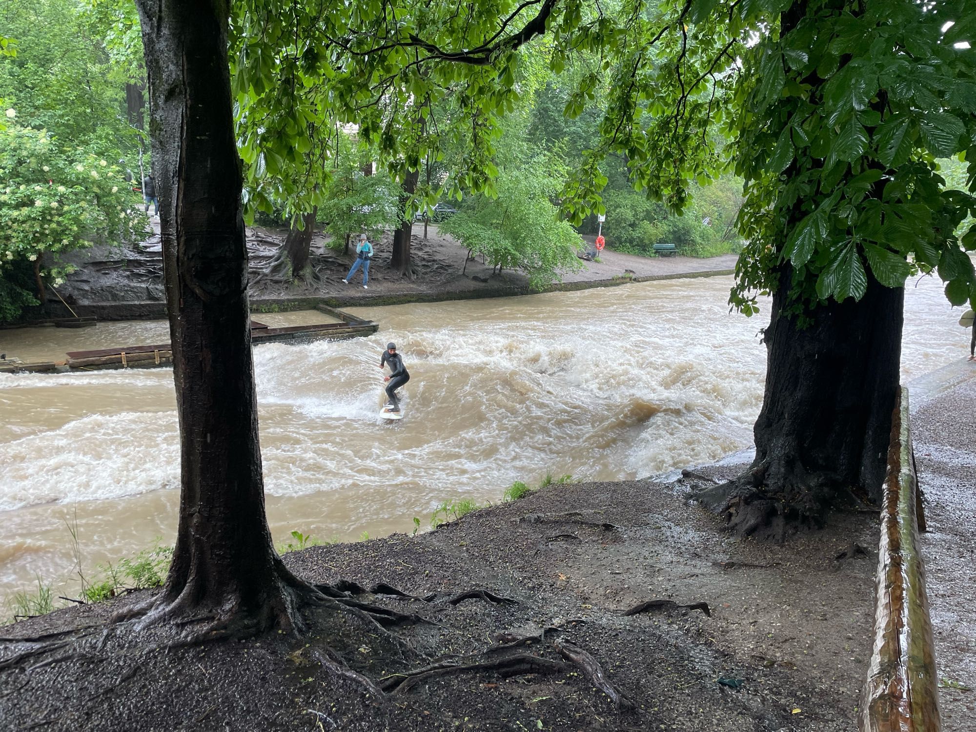 Ein Surfer auf der Eisbachwelle in München. Durch das Hochwasser ist die Welle höher und das Wasser braun