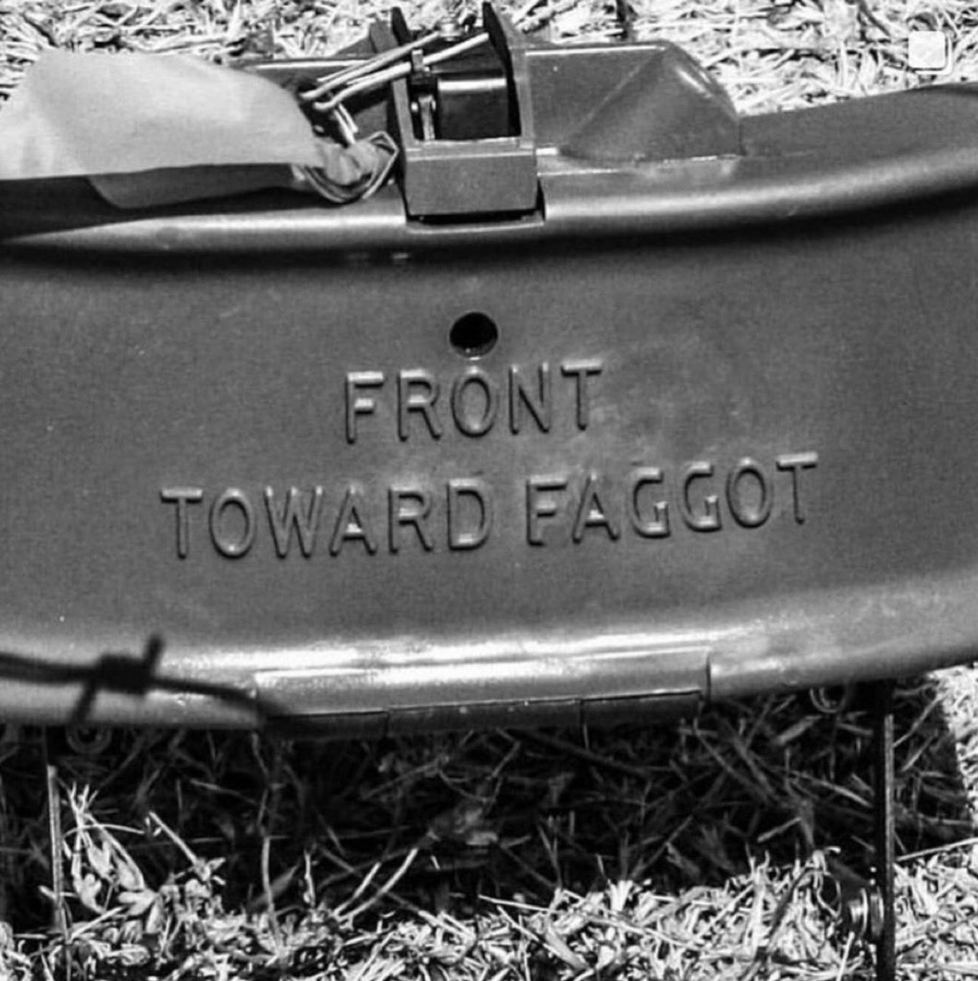 A Black/White image of a Claymore mine. The "Front toward enemy" text on the front of the mine has been replaced with "Front Toward Faggot"