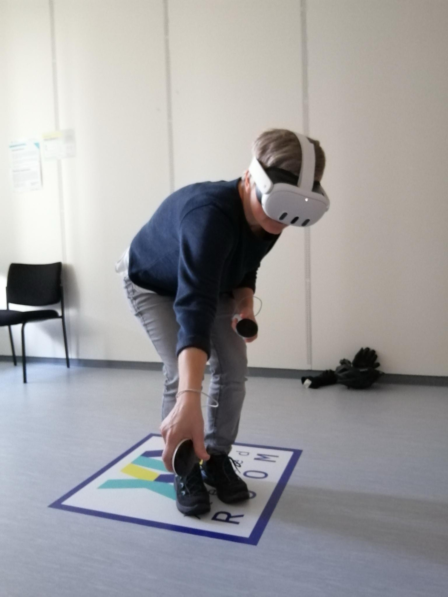 Tatjana with VR glasses and controllers , crouching to pick something up