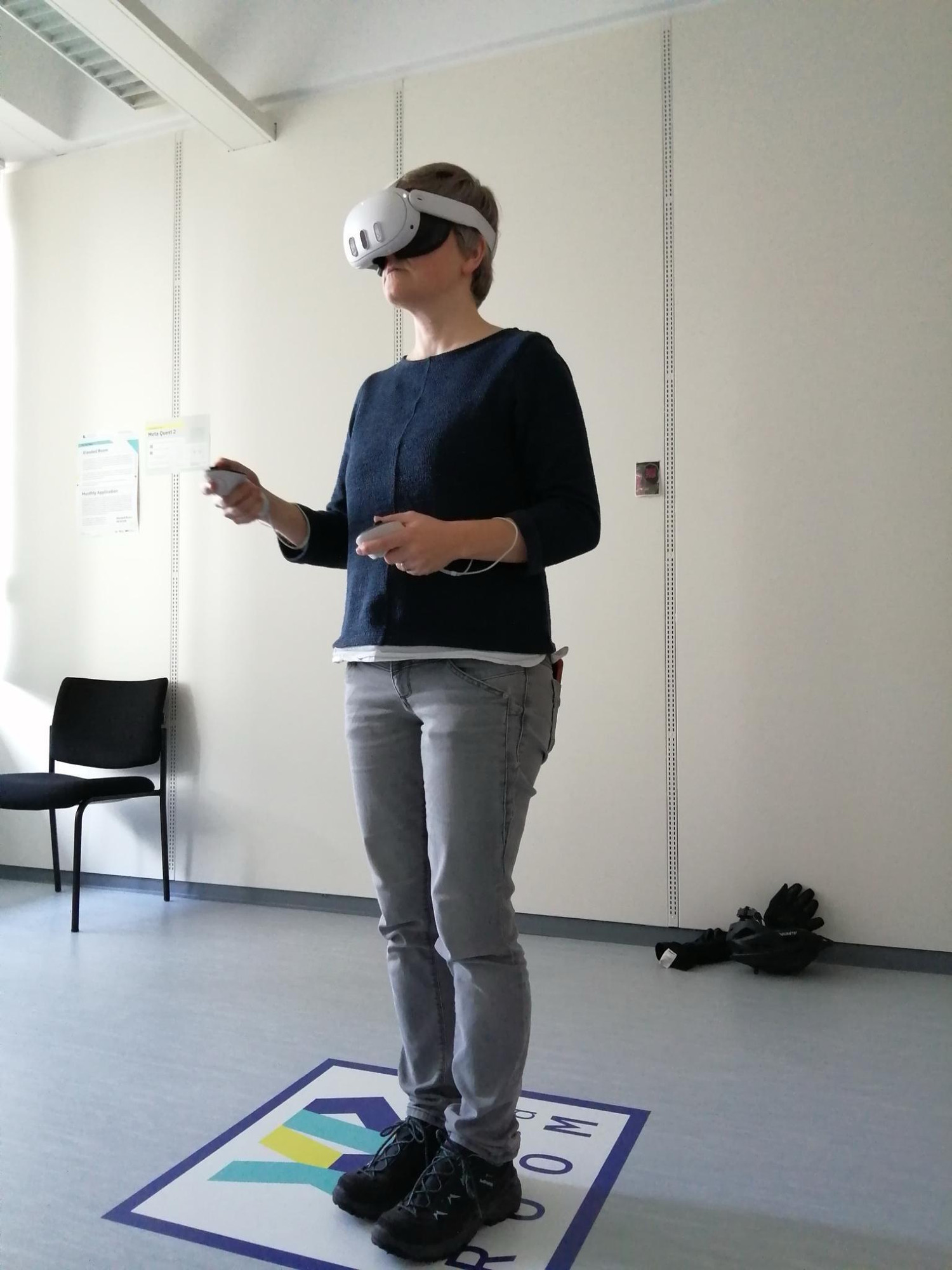 Tatjana with VR glasses and controllers , standing and looking straight ahead 