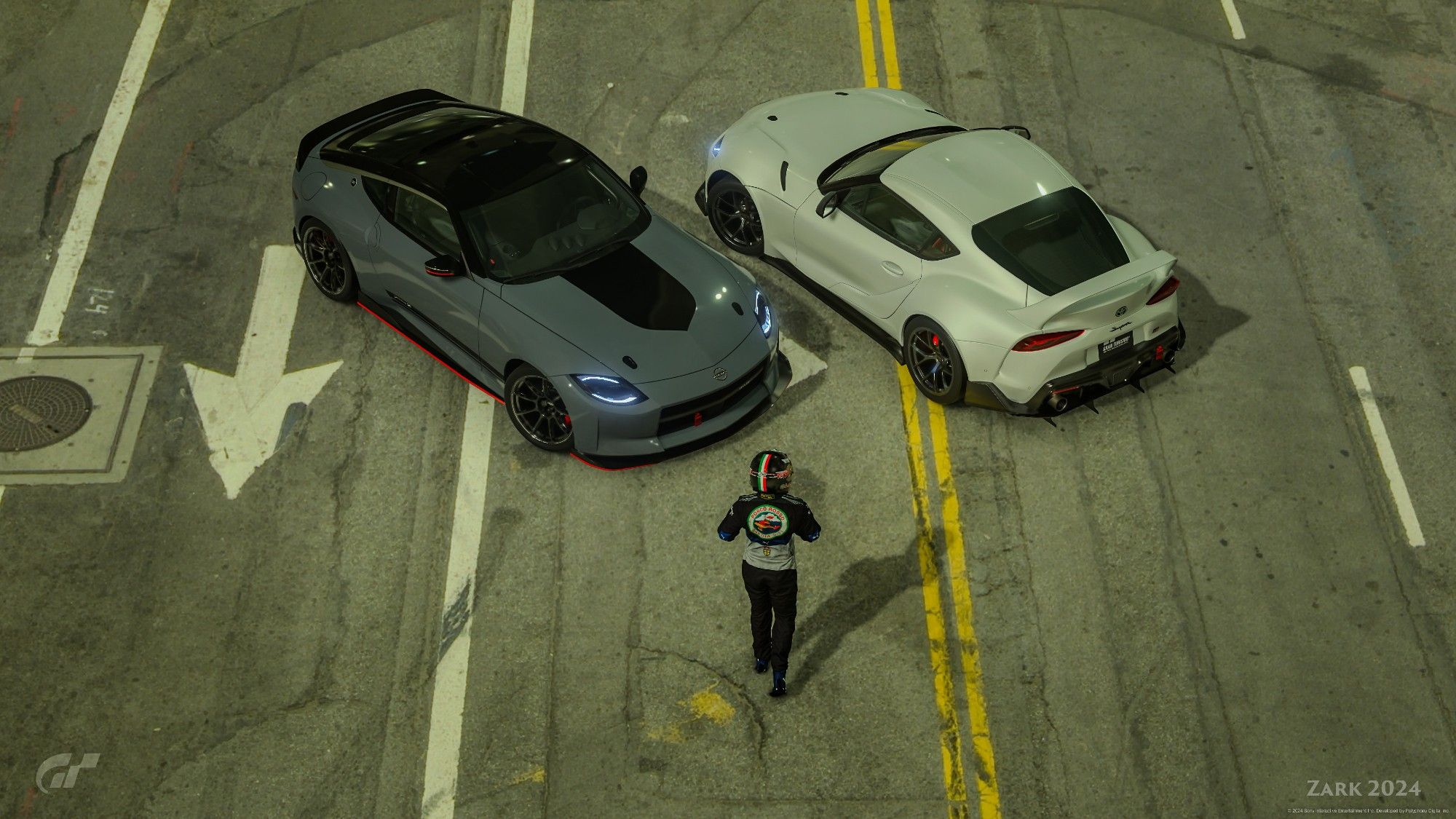 In the a freeway tunnel in Los Angeles, California, USA, a man in a racing suit and helmet walks towards two custom sports cars, a 2023 Nissan Z to his left and a 2019 Toyota GR Supra to his right.