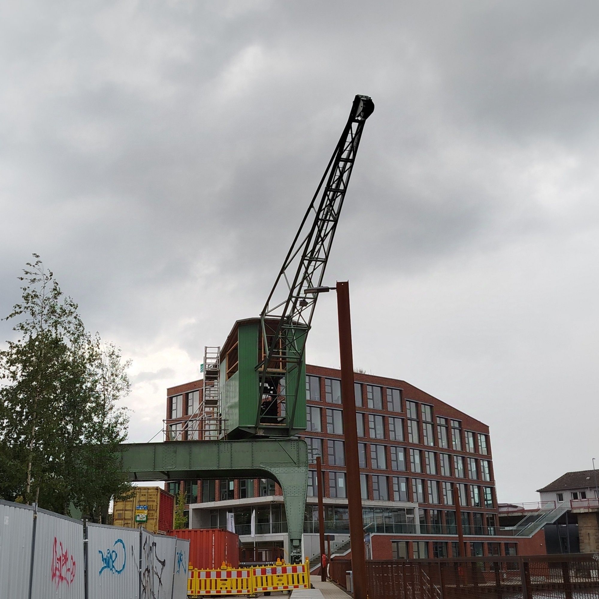 Foto des Portalkrans, dahinter das Gebäude des Fraunhofer Instituts. Dunkler, wolkiger Himmel.