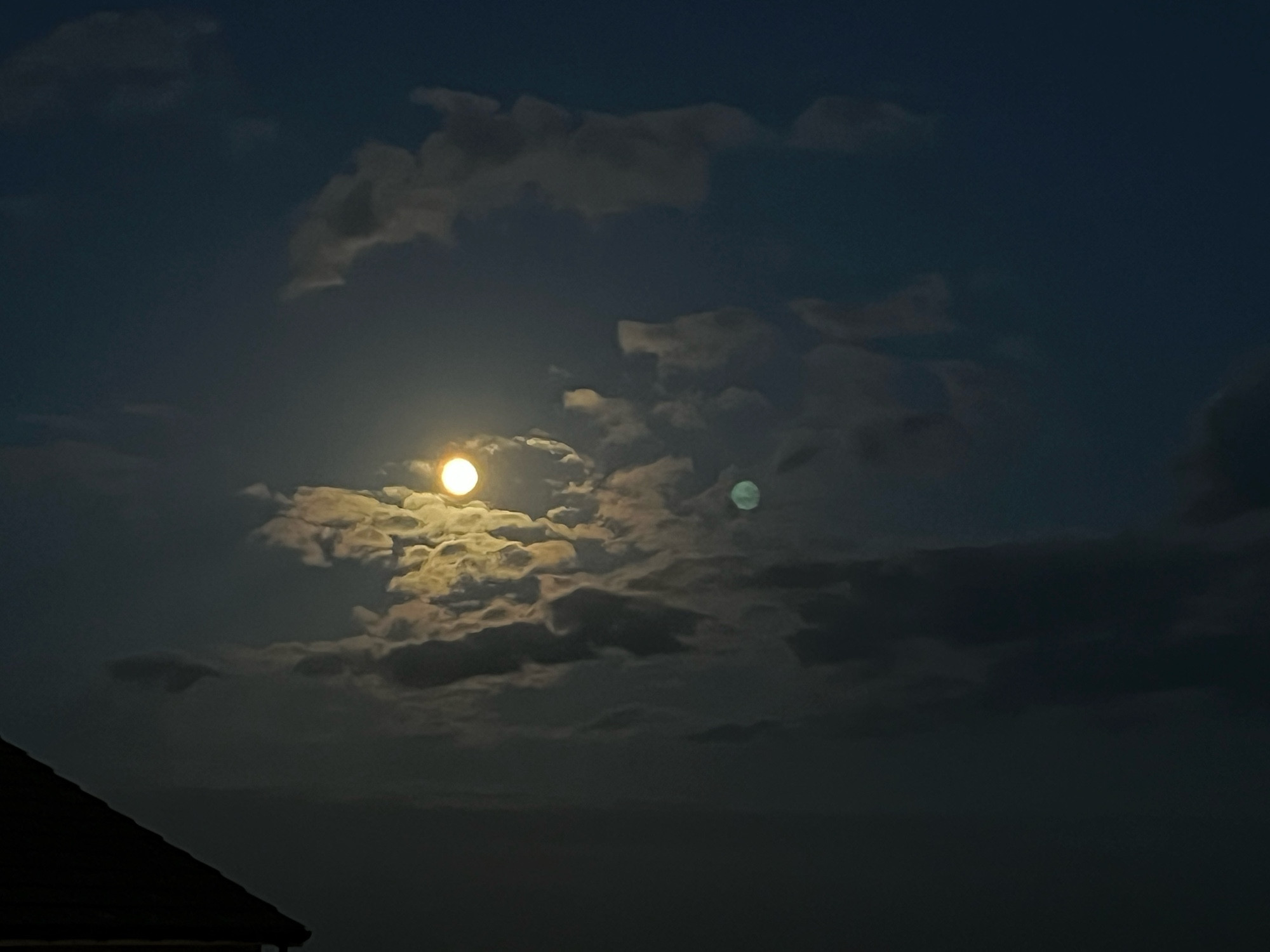 A rising moon surrounded by a small clouds