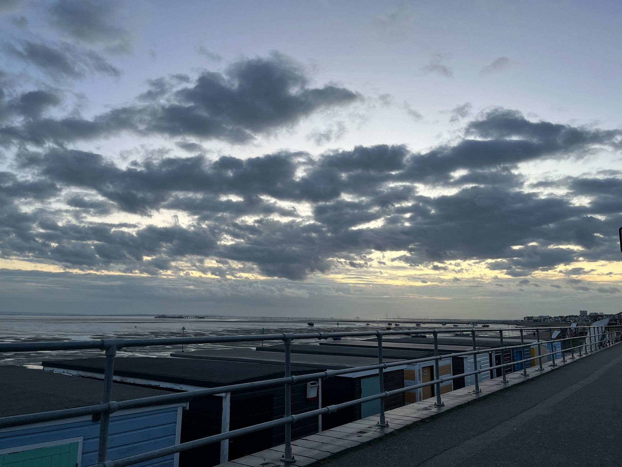 Cloudy dusk looking out over the roof of beach huts towards the pier