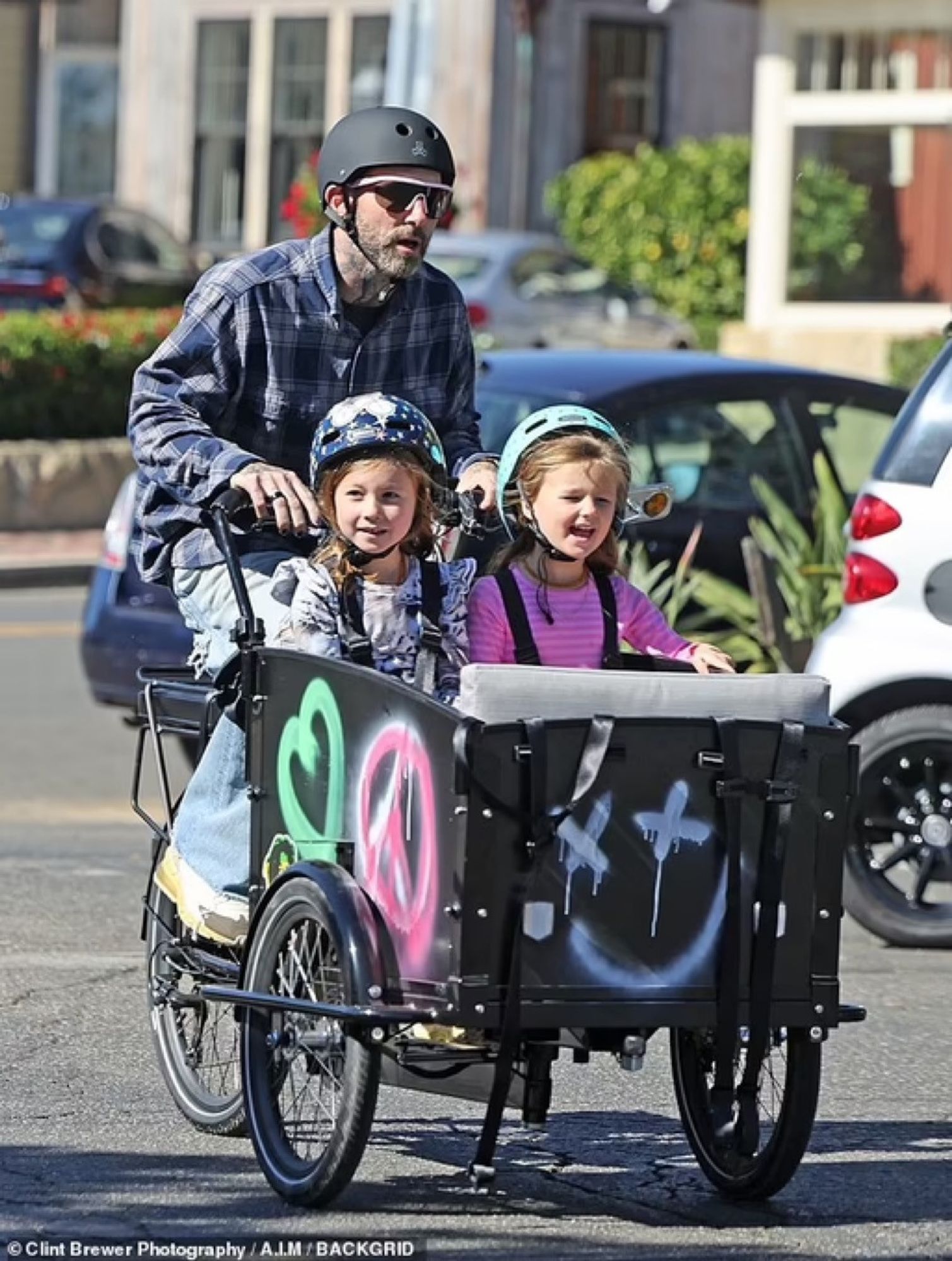 Singer Adam Levine on a bakfiets like bike w/ his daughters in it.