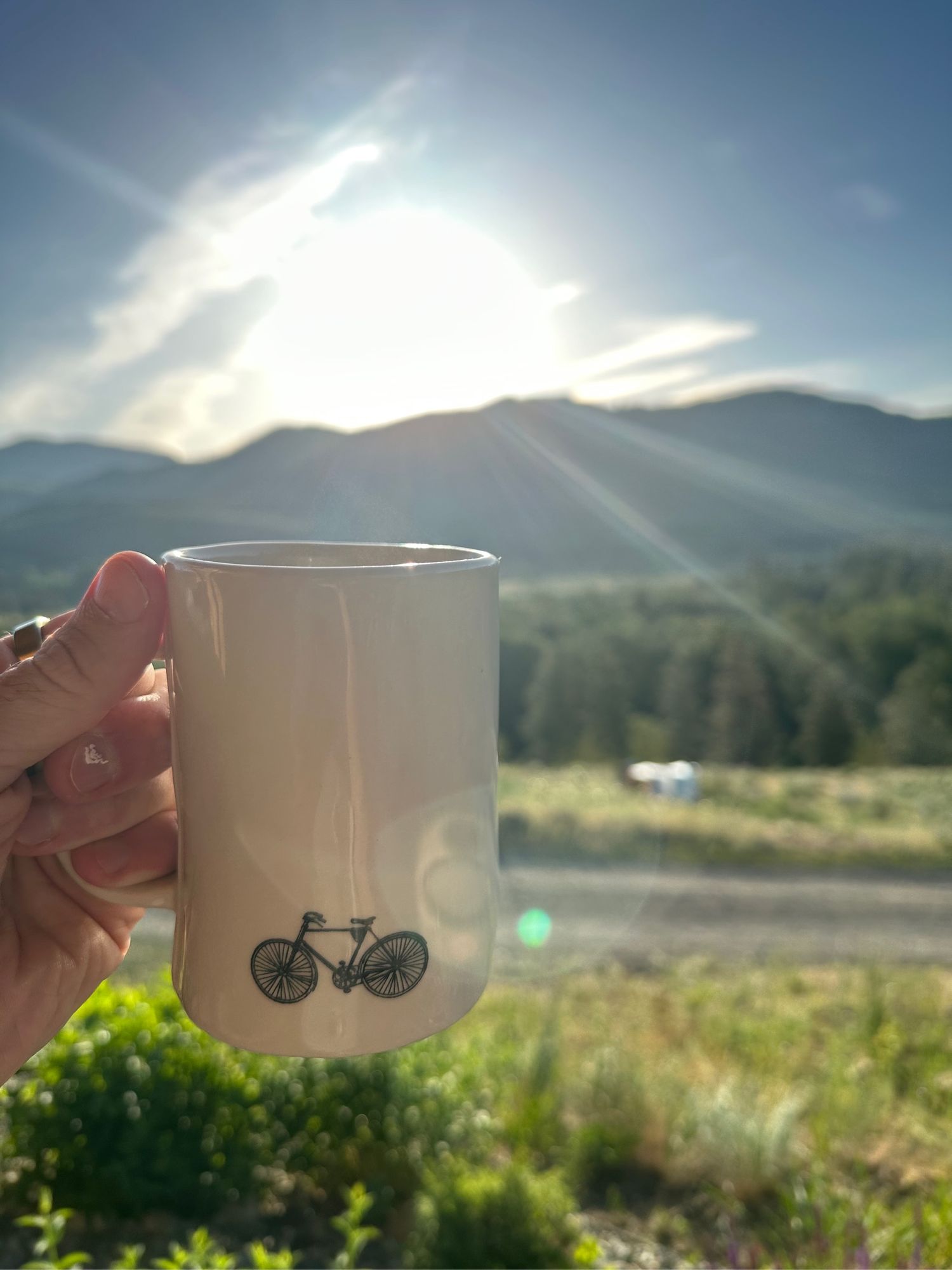 Hand holding a coffee mug with clouds in the background 