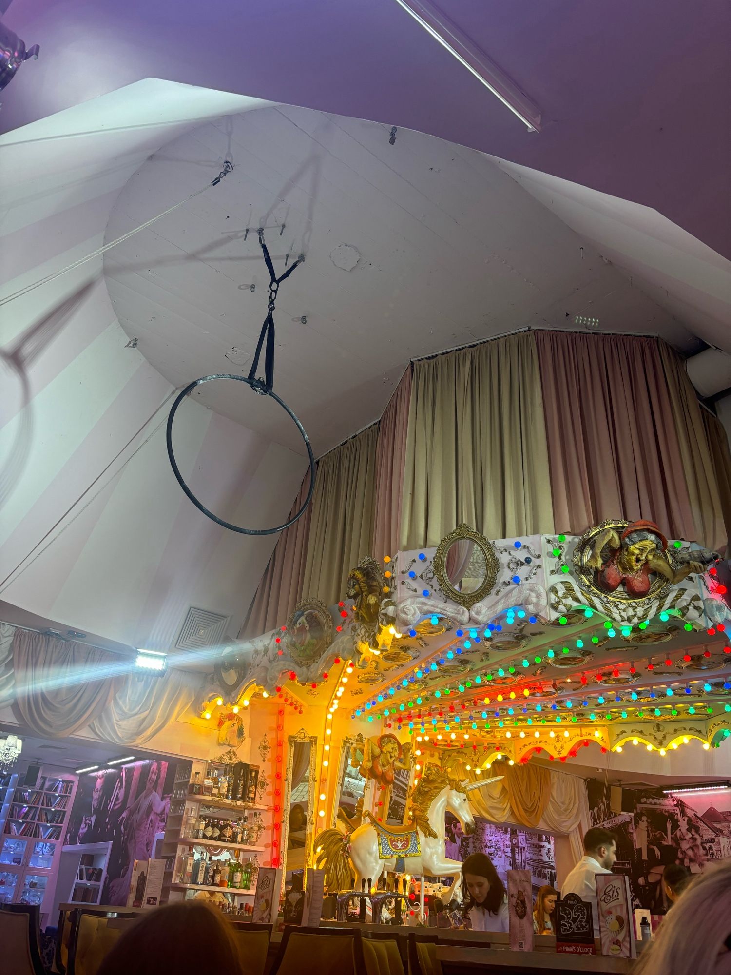 The Circus Bar in Berlin, coloured lights like a carousel over the bar and a hoop hanging from the ceiling