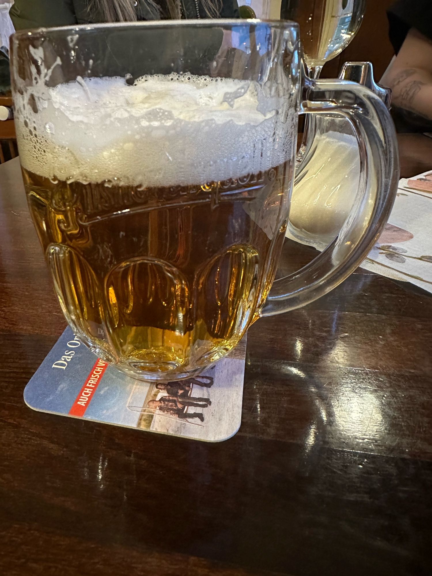 A glass of Pilsner Urquell on a dark wooden table