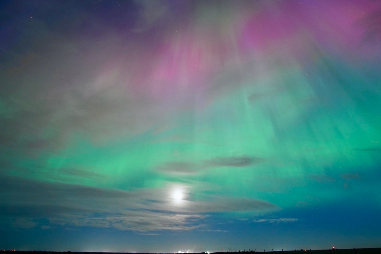                                Looking south toward the moon. Green aurora surrounds it, with red above. There are also clouds obscuring it scattered across the sky 