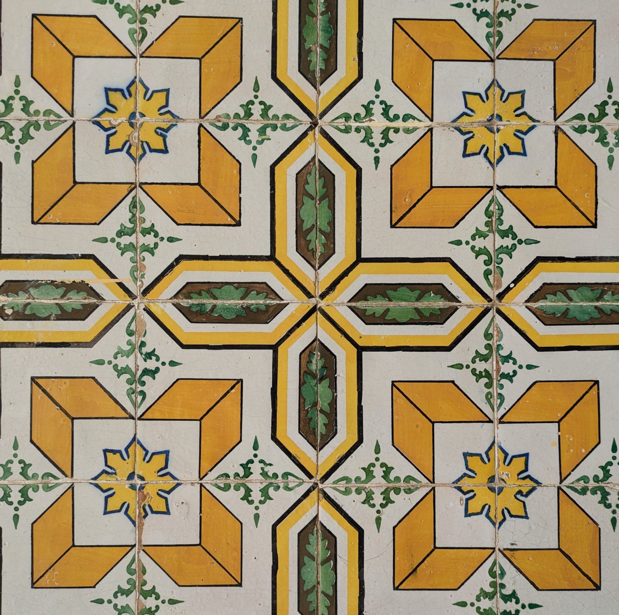 A geometric pattern of gold and green, decorative Portuguese tiles as seen on an exterior wall in Lisbon.