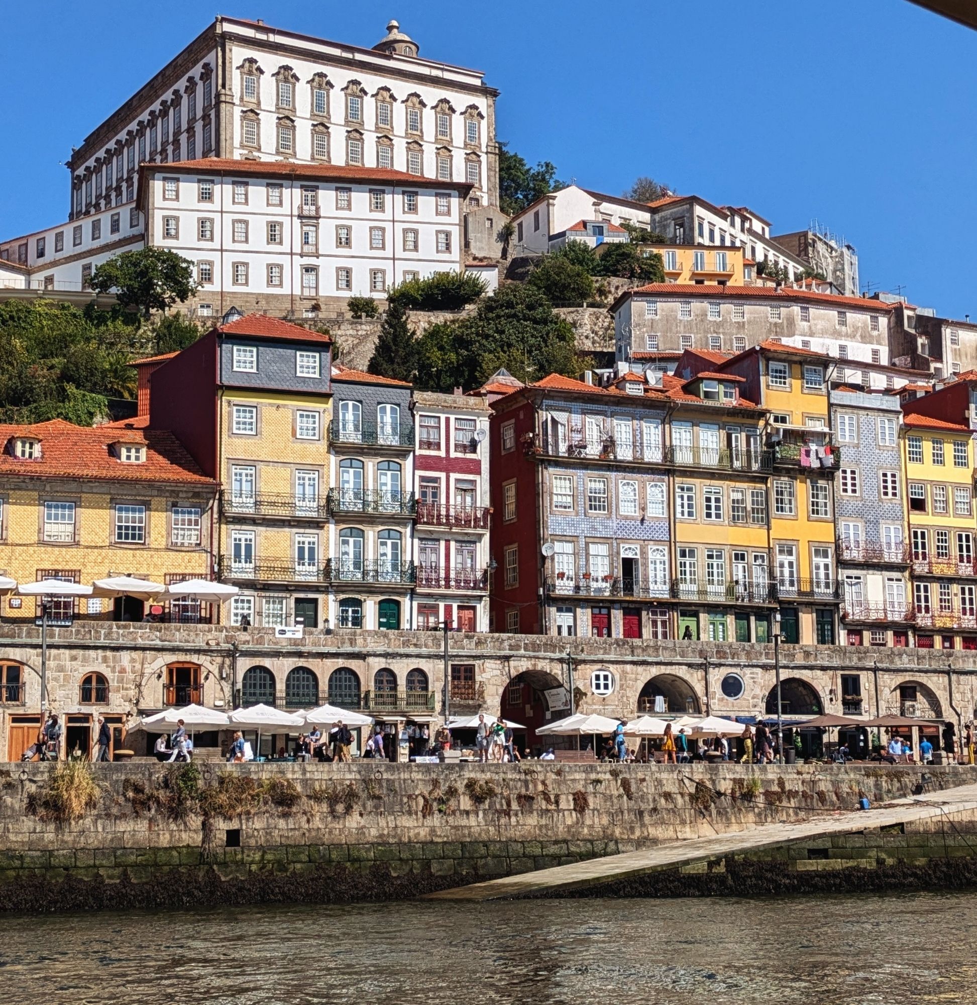 Tall, skinny houses decorated with vivid red, blue, and yellow tiles line the River Douro in the city of Porto.