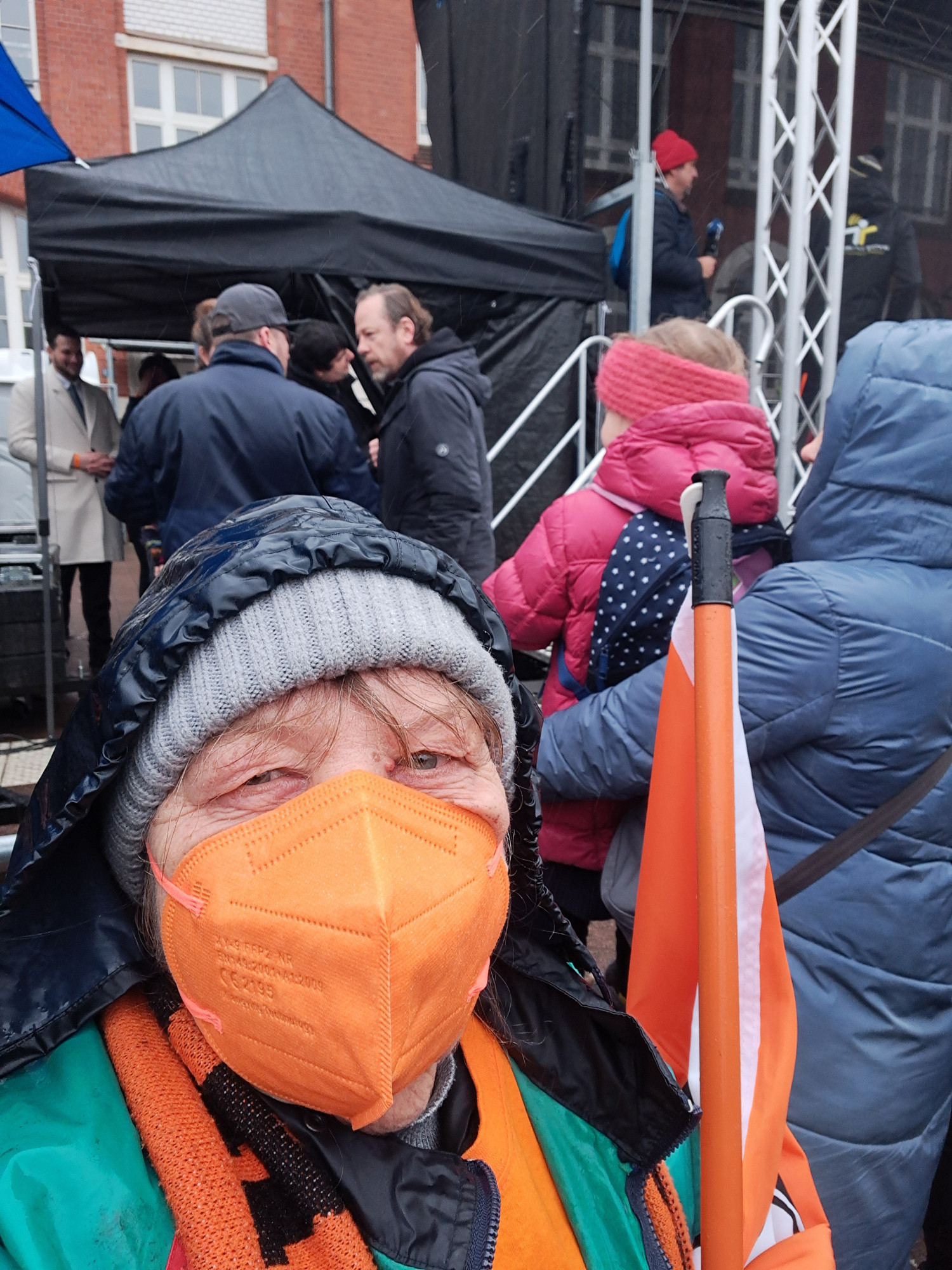 Meine Person vor der Bühne, auf der Demo #WirSindDieBrandmauer mit oranger FFP2 Maske.