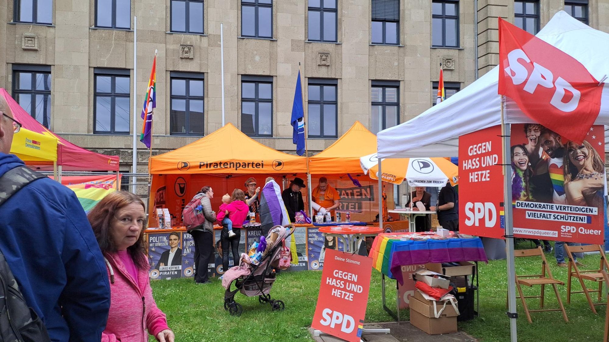 Zu sehen ist ein Foto vom #CSD in Düsseldorf. Piratenpartei Infostand. Im Vordergrund ein Infostand der SPD.