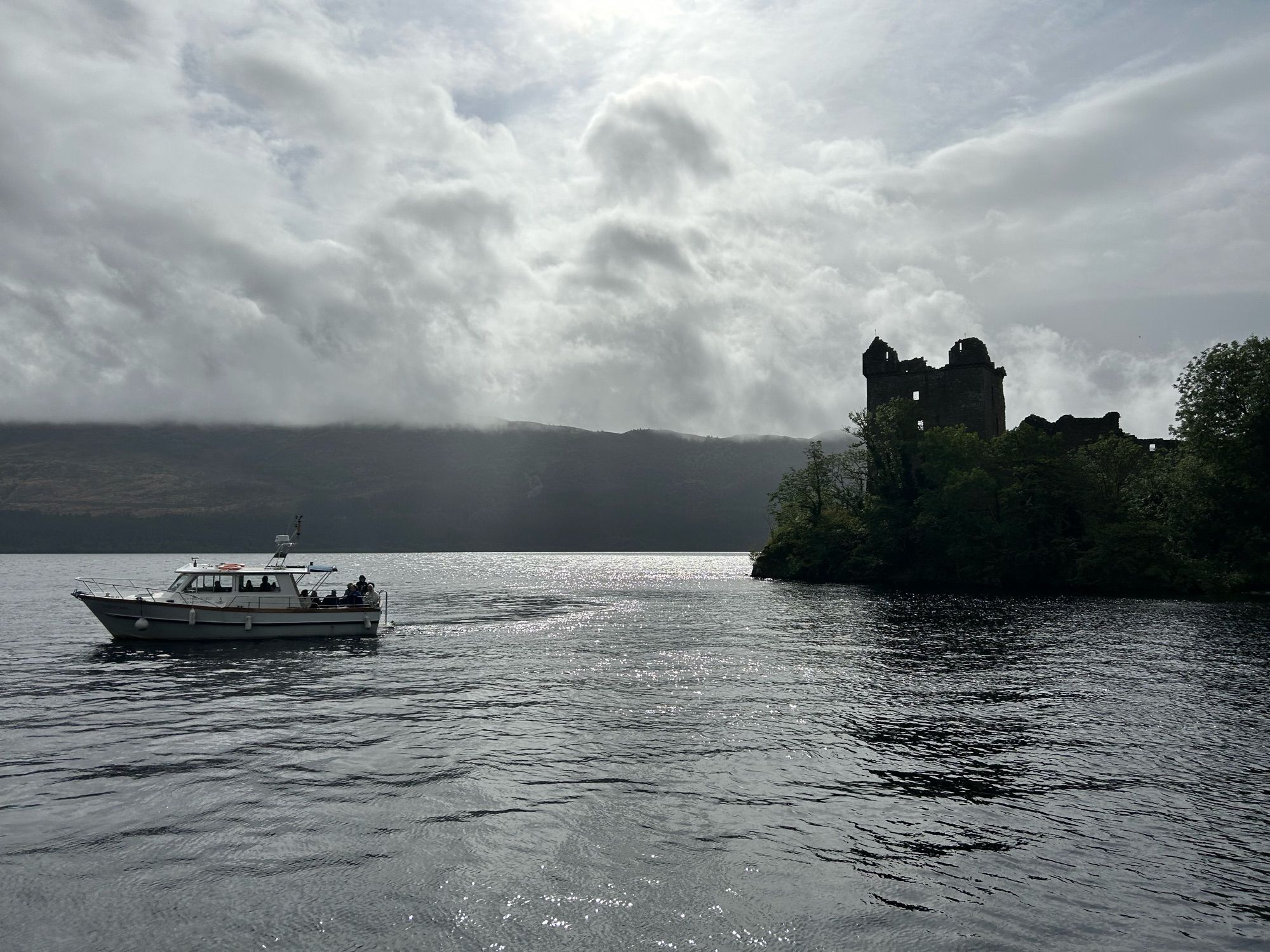 Urqhart castle, on Loch Ness. The remains of a stone turret standing on the edge of a lake.