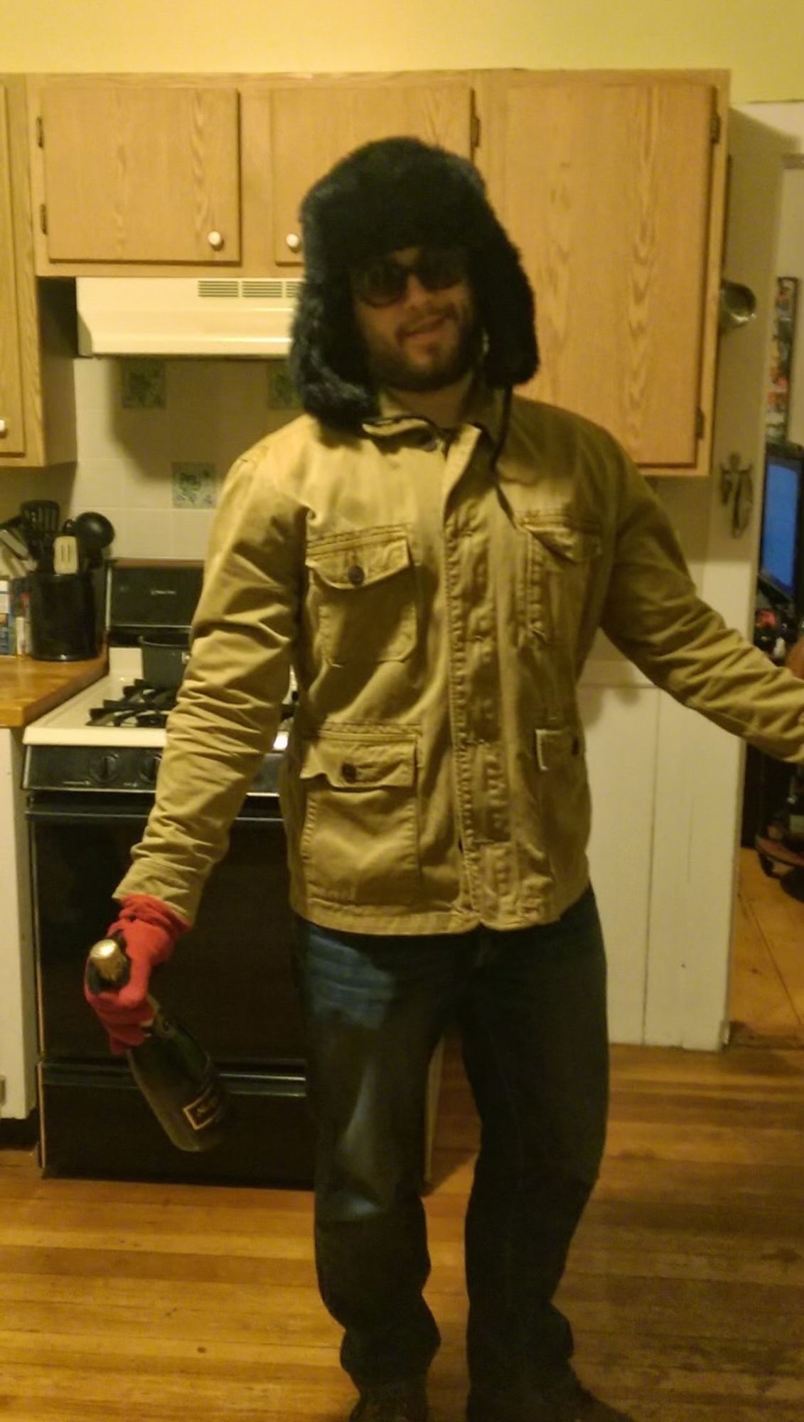 Yours truly, bottle of bubbles in hand, black faux fur hat and sunglasses on, posing for a photo in a dated apartment kitchen before braving a walk in a snowstorm