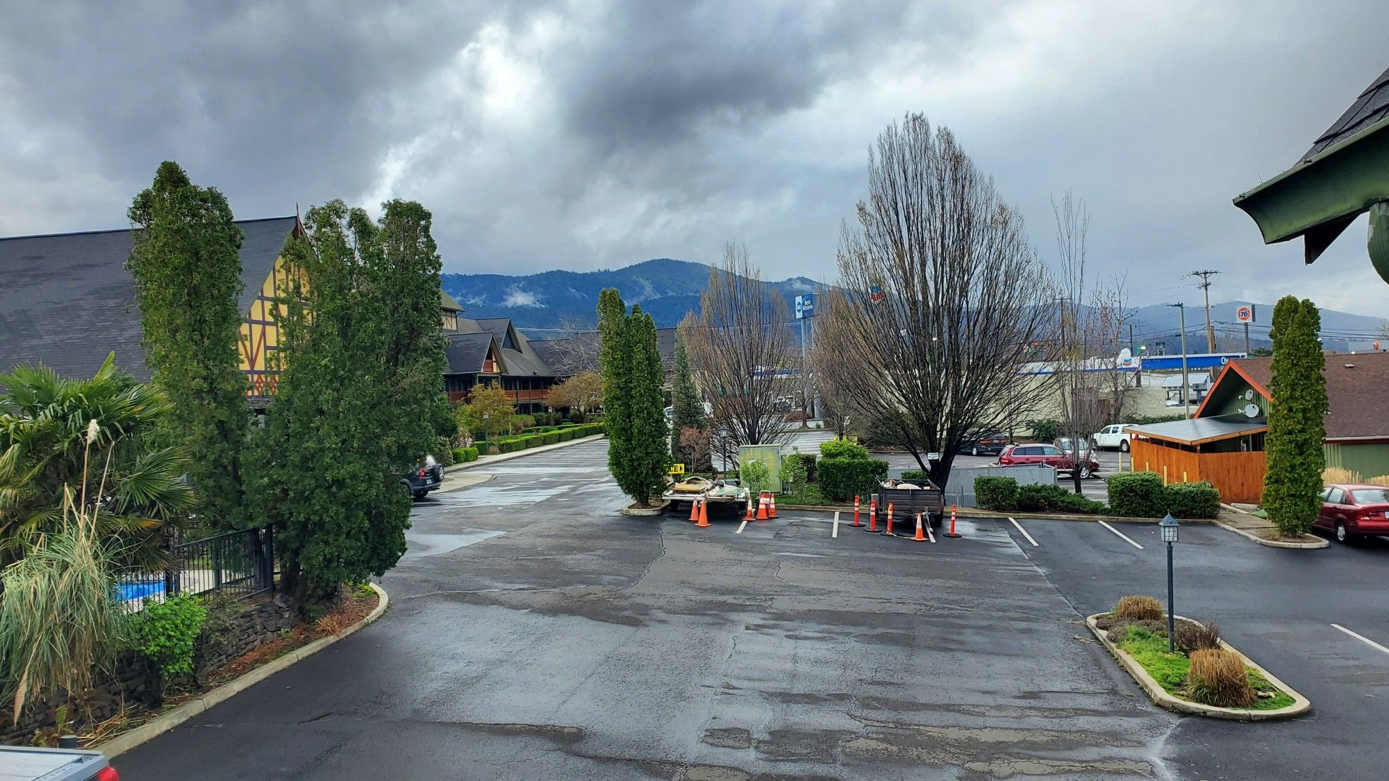 Fairly picturesque view from the hotel. Mostly featuring the parking lot but with plenty of vibrant greenery and a stretch of tree dense hill line under a Grey and cloudy sky