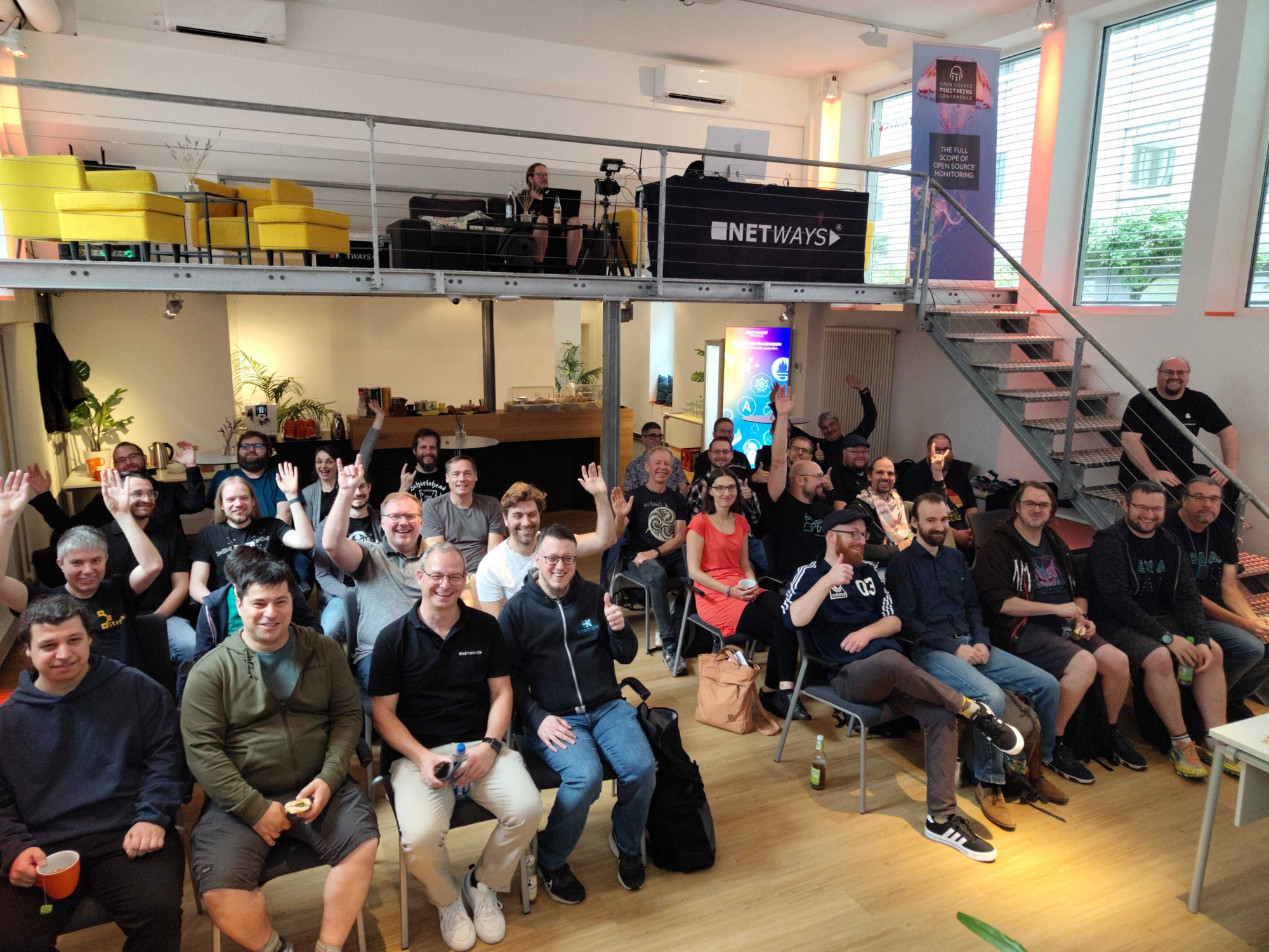 A group photo of the enthusiastic OpenVox fans who made it to Nürnberg for the first annual VoxConf. There are about 30 people in the room, waving and cheering.