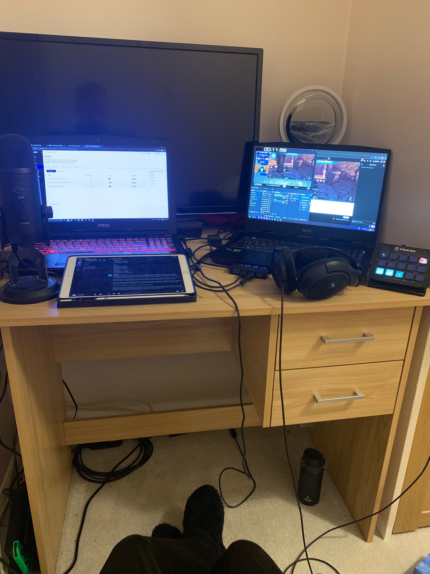 a desk with two laptops, an ipad, a Stream Deck, a microphone, and several wires. i’m also wearing warm socks because comfy