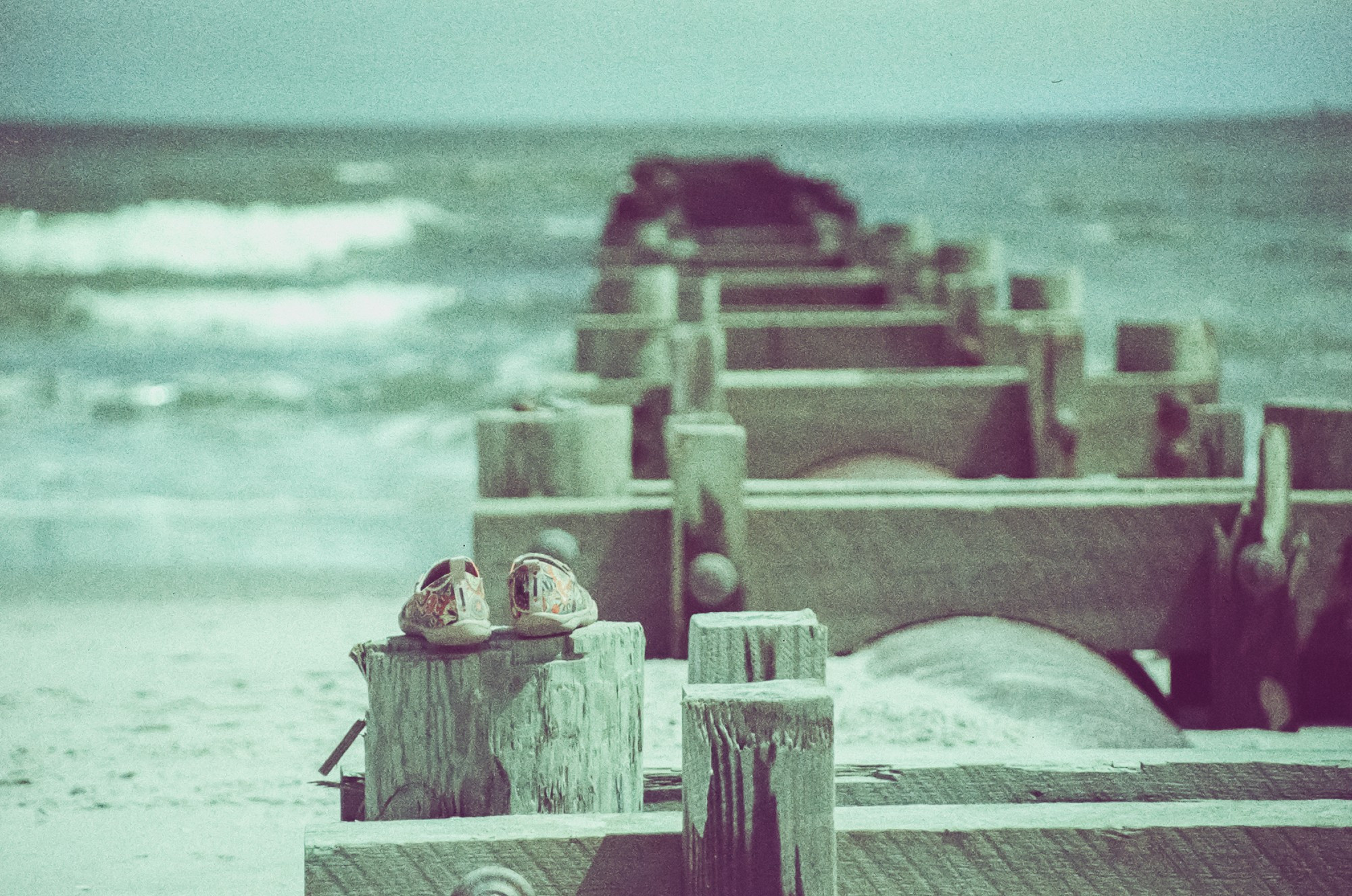 My shoes, sitting on top of a log that's part of a storm water drainage pipe on the Ocean City beach. The shoes are in focus, while the rest of the pipe and the ocean beyond are soft and out of focus.