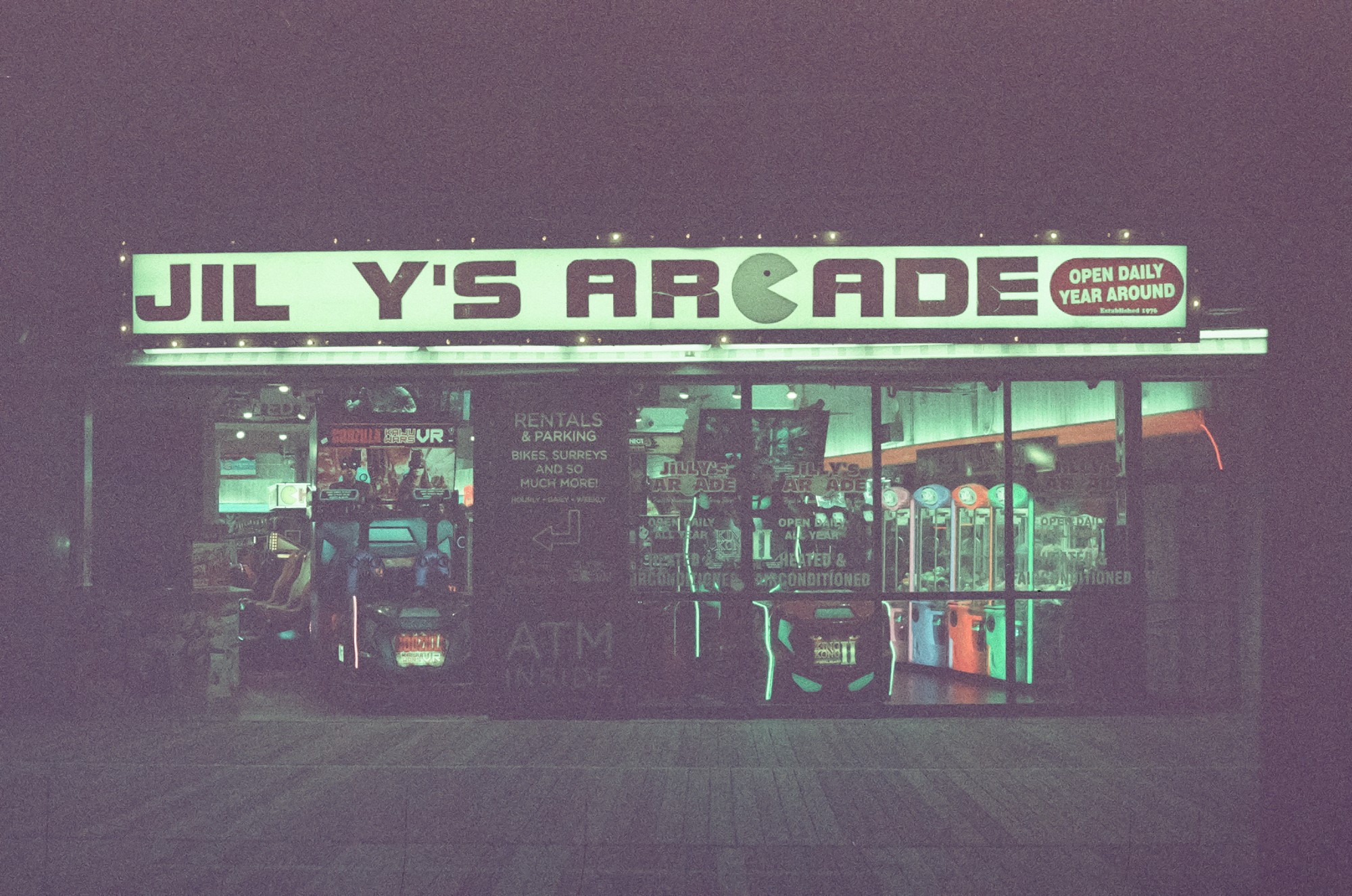 Jilly's Arcade, all lit up on a dark boardwalk. The second L in "Jilly's" is missing.