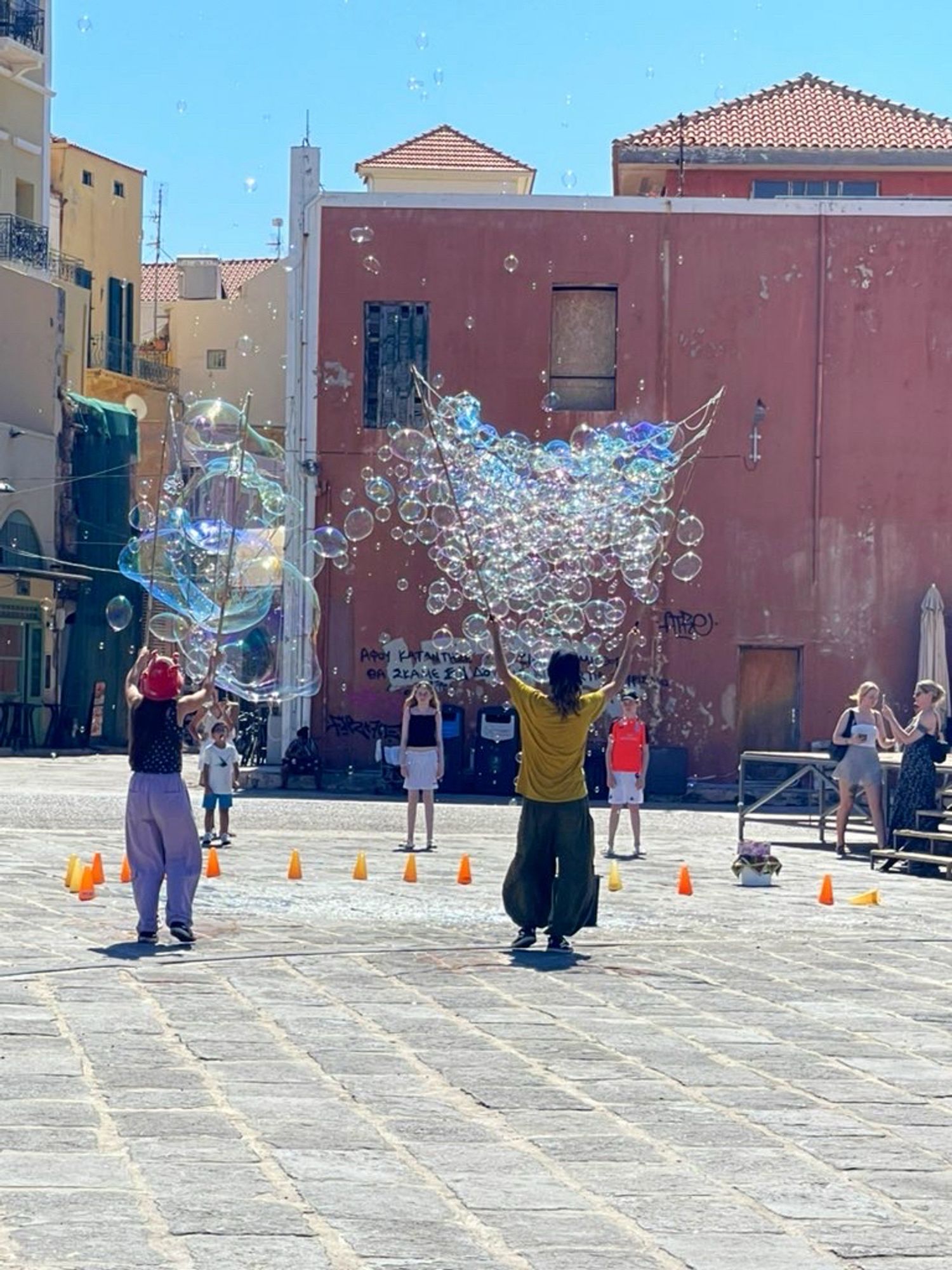 Straßenkünstler in Chania, nahe des alten Hafens, die mit langen Stöcken, Seilen und Seifenlauge riesige Seifenblasen zaubern