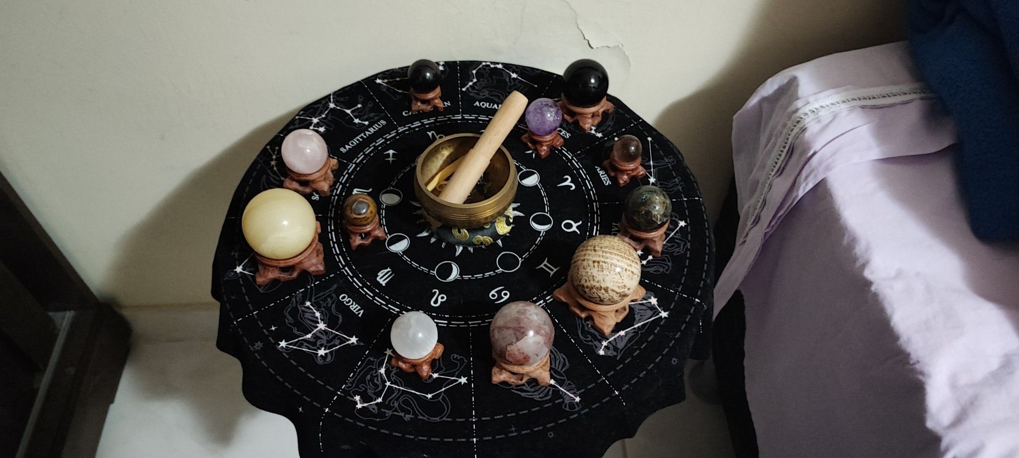 table with the zodiac circle, and spheres of crystals representing each planet and luminary. in the middle, a meditation bowl.