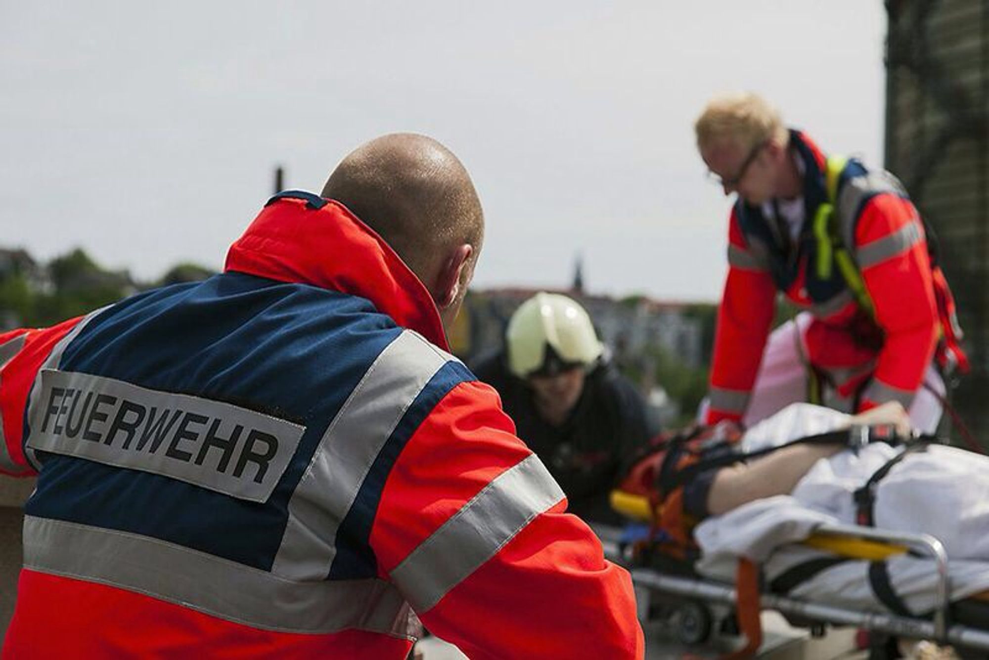 Das Bild zeigt zwei Feuerwehrleute, die eine Person versorgen, die auf einer Bahre liegt. Foto: Stadt Wuppertal