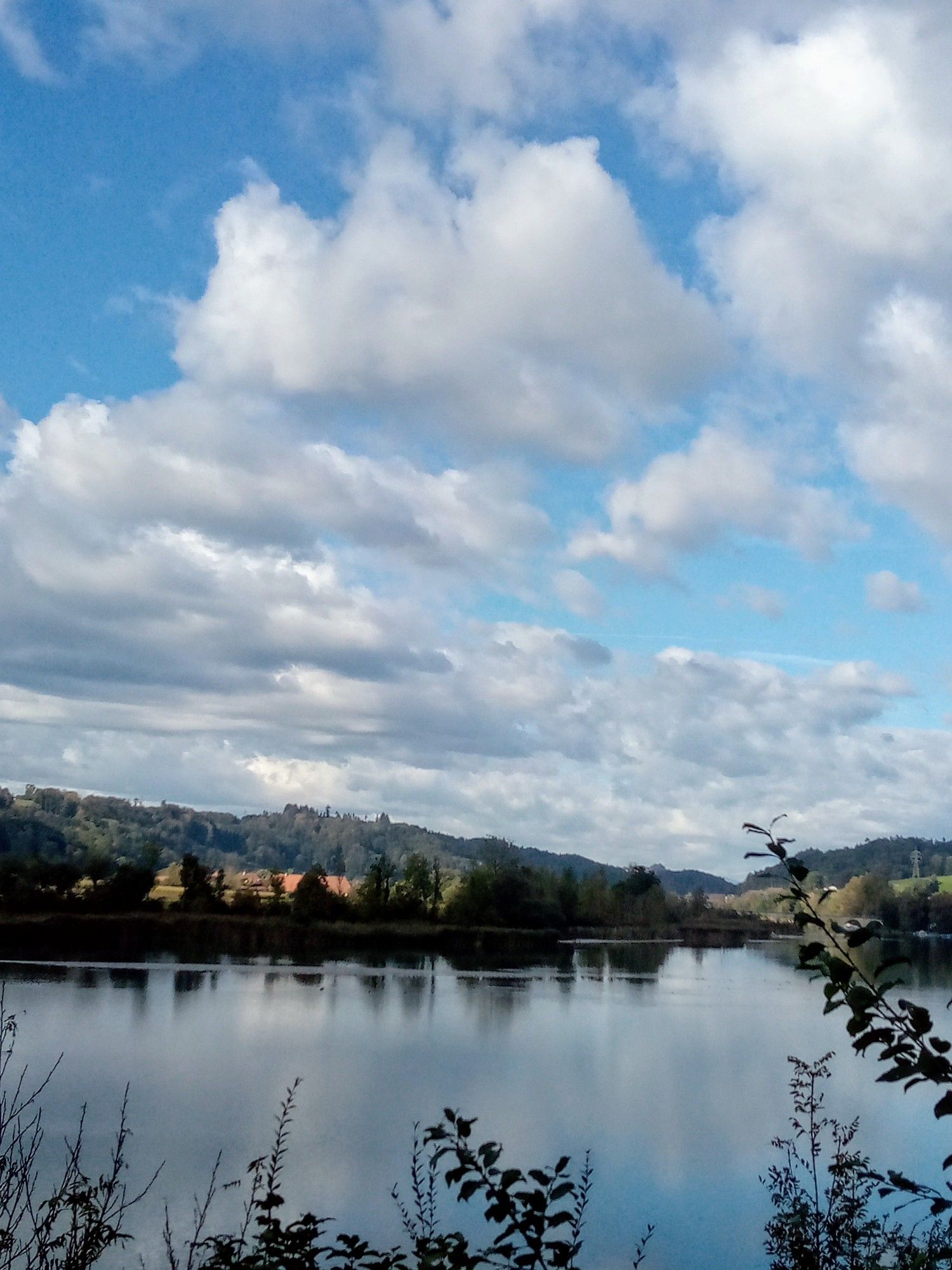 Blauer Himmel mit vielen Wolken gespiegelt im See