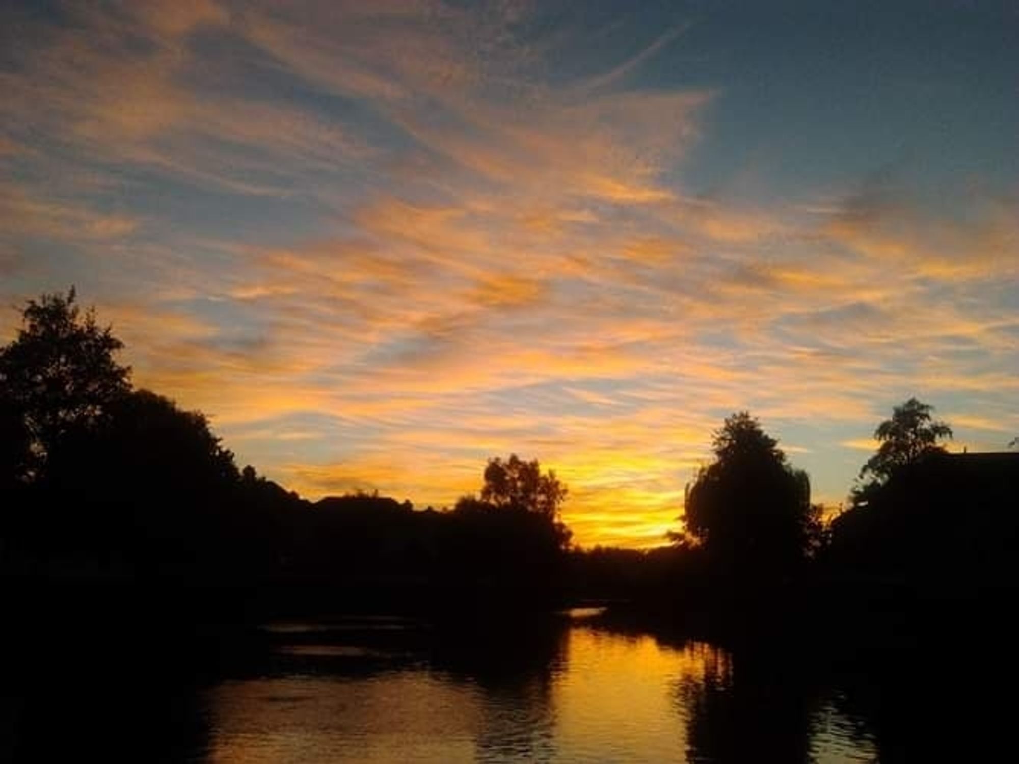 Sunset, clouds, trees, and water.