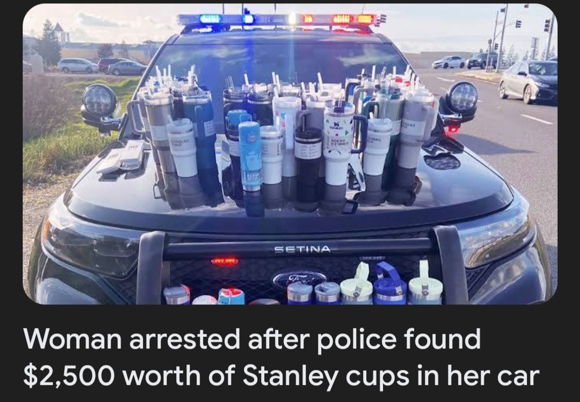 Hood of cop car, lights flashing, covered in $2500 worth of Stanley cups.