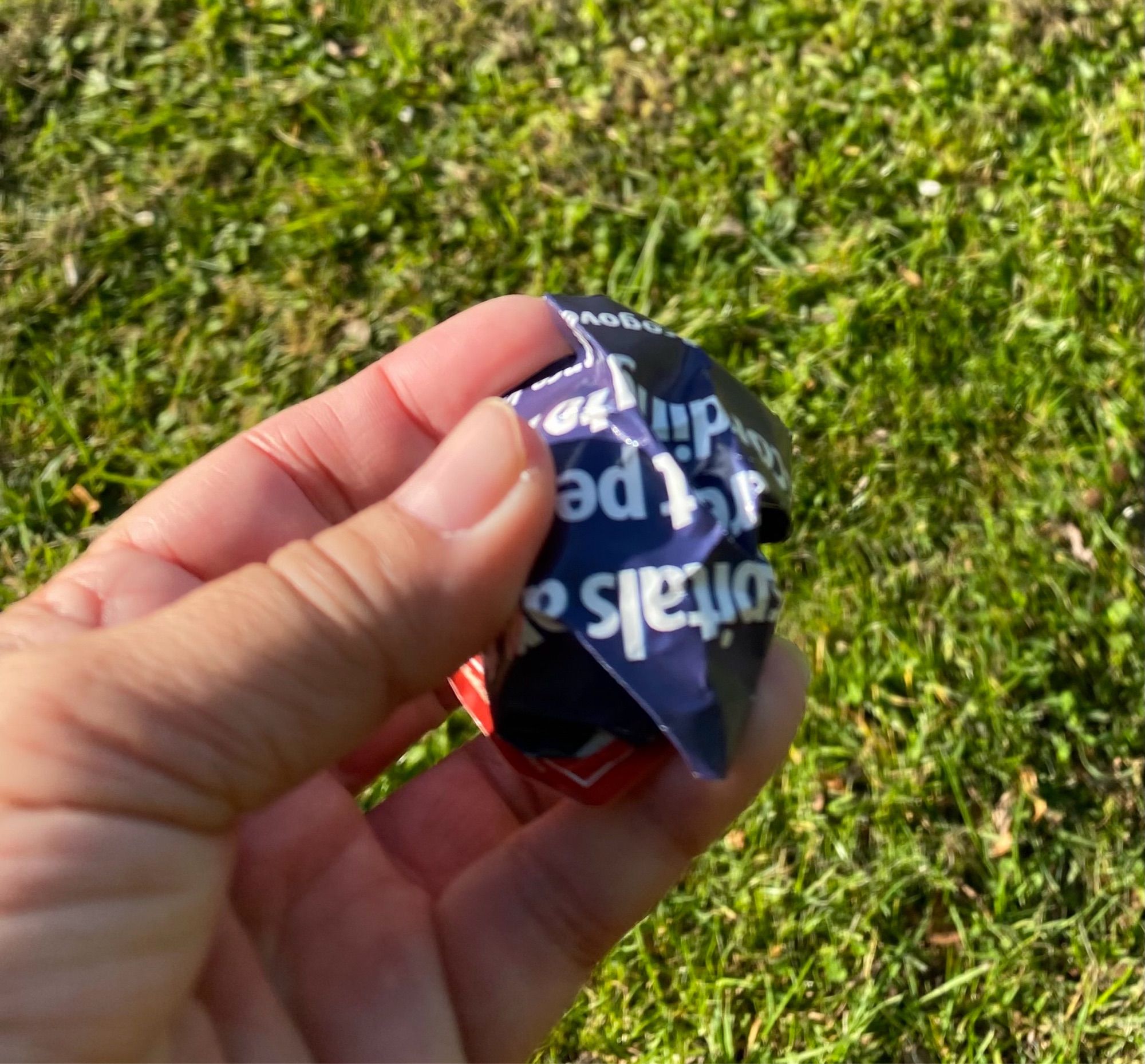 A left hand holding a crumpled ball of racist stickers that have been removed from lampposts.