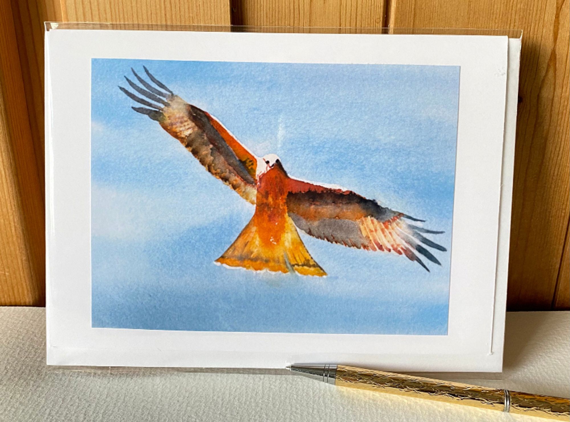 A beautiful red and brown Red Kite eagle soaring overhead in the sky. A handmade watercolour greeting card to wow your friends and relations