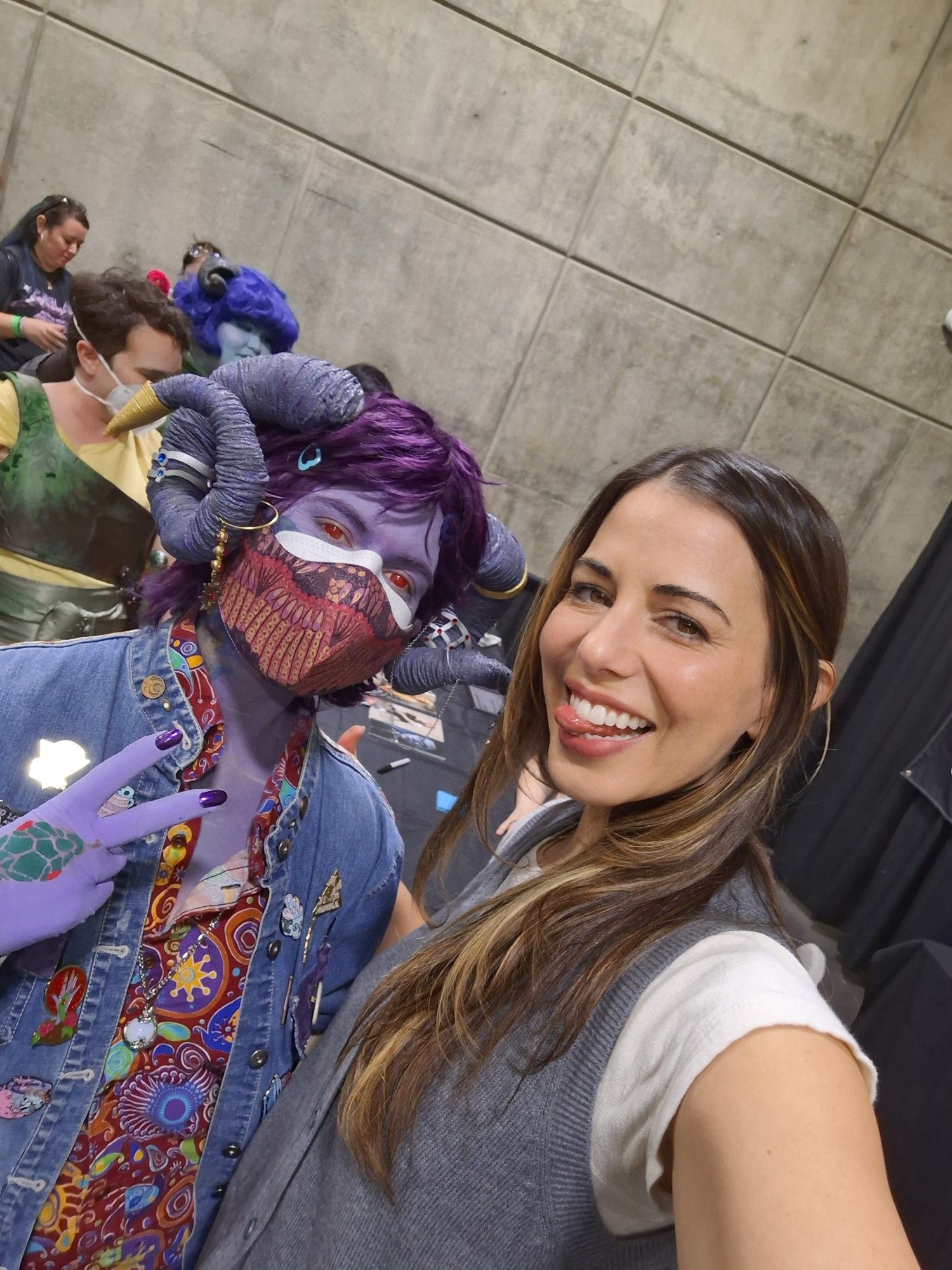 selfie of modern mollymauk cosplayer throwing a peace sign next to laura bailey who is sticking her tongue out while smiling.