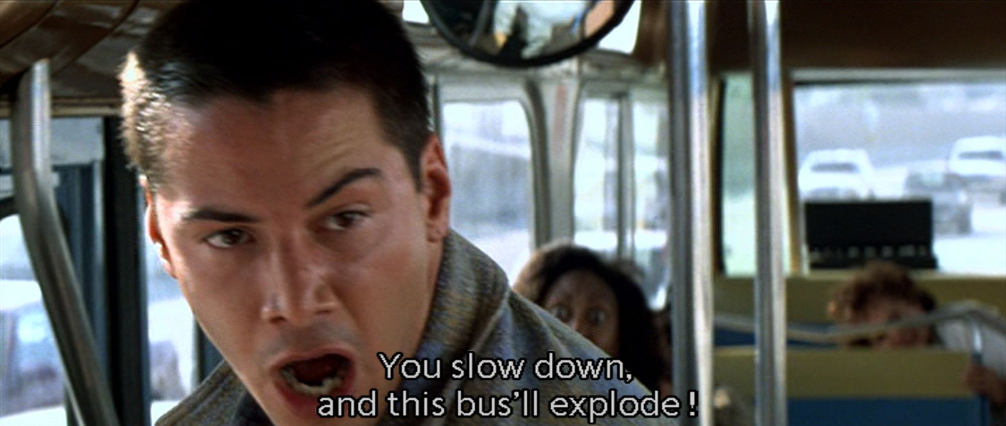 a closeup of Keanu Reeves on a bus yelling. The caption reeds 'You slow down, and this bus'll explode!'