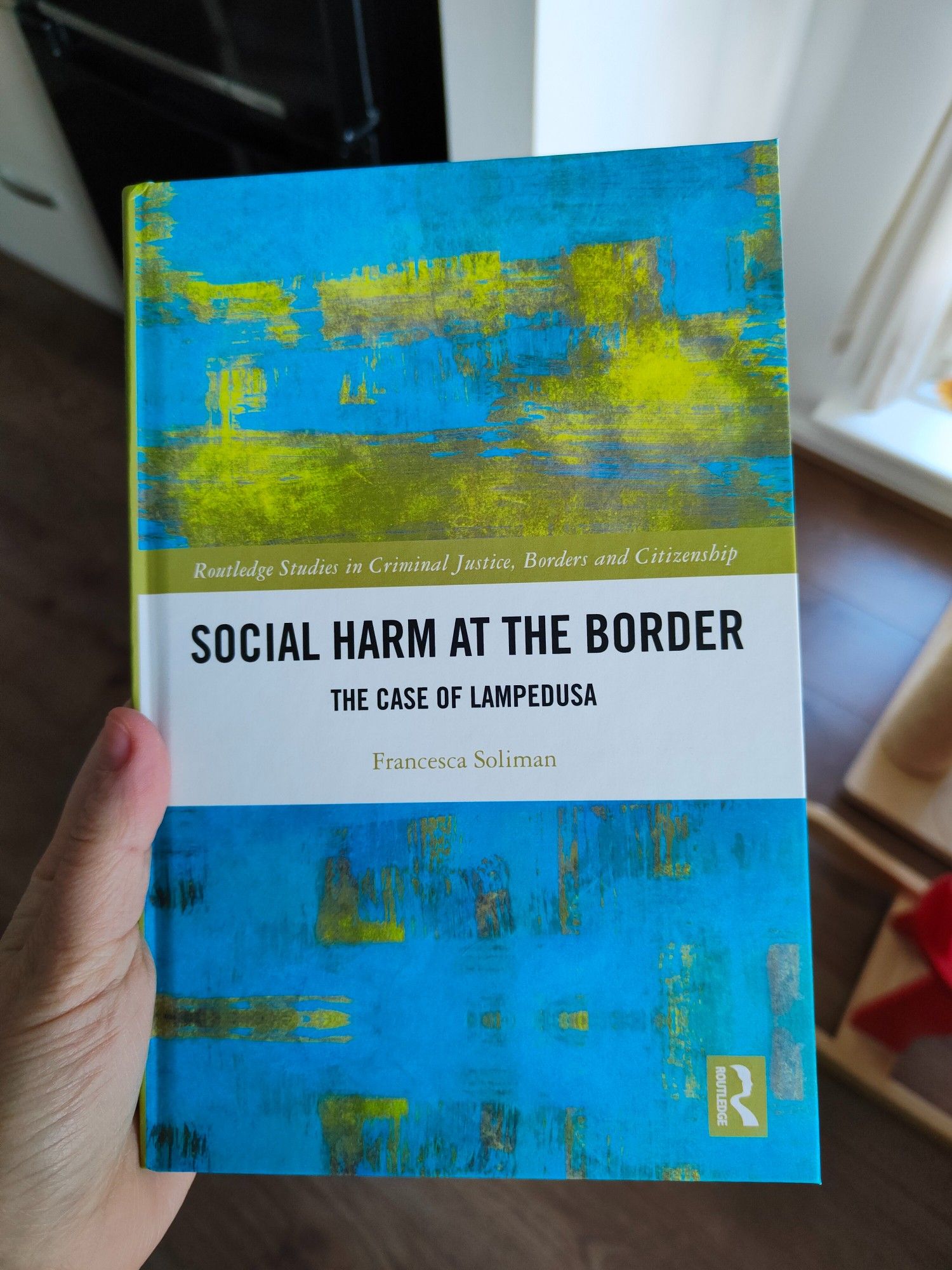 A book with a blue and gold cover, titled "Social harm at the border: the case of Lampedusa", by Francesca Soliman