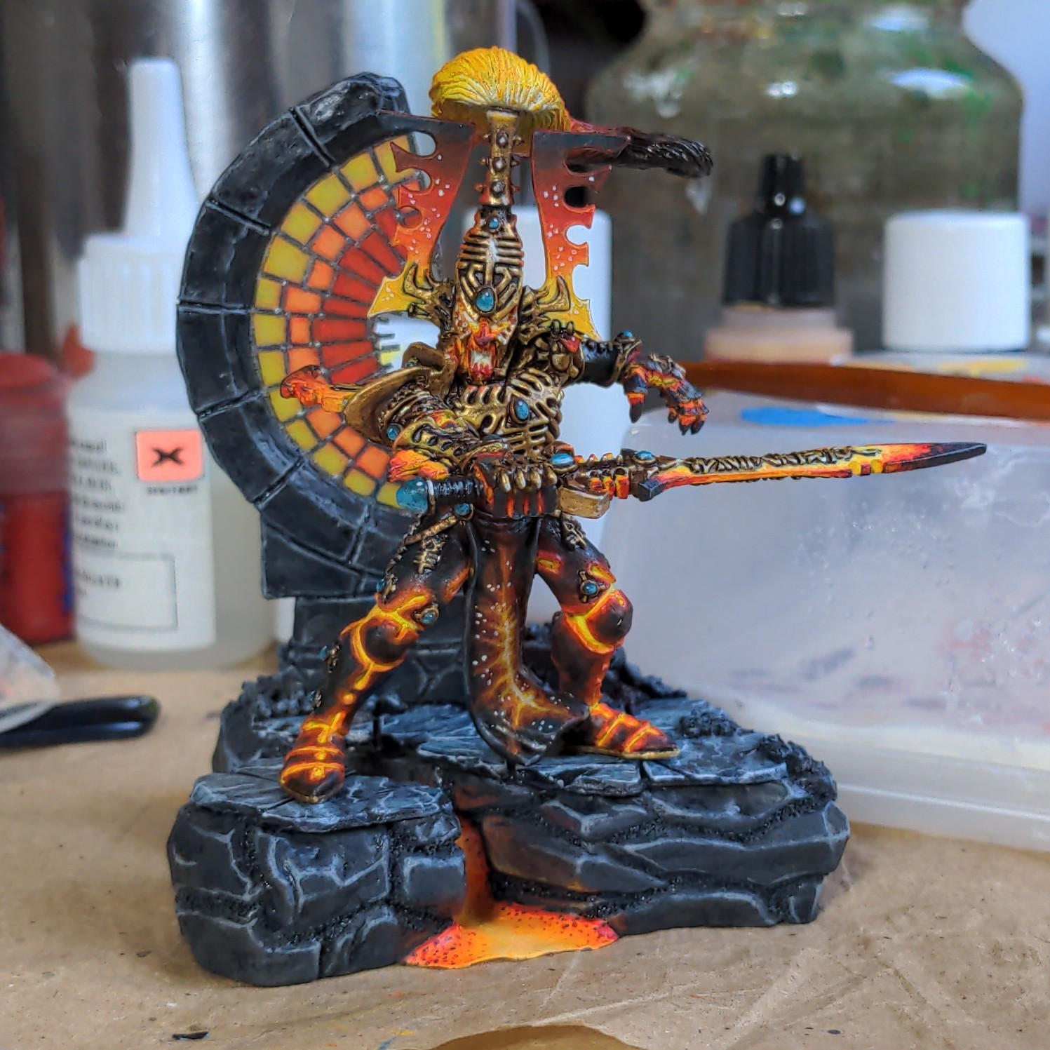 A model of the avatar of khaine from warhammer 40k painted black, orange, red and yellow.