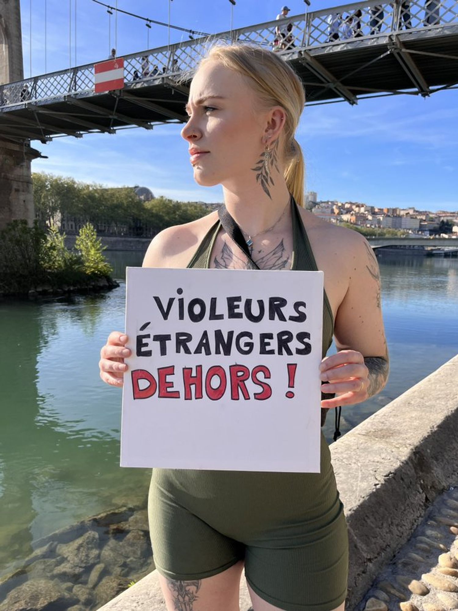 Mila Orriols sous un pont à Lyon, elle tient une pancarte "Les violeurs étrangers dehors"