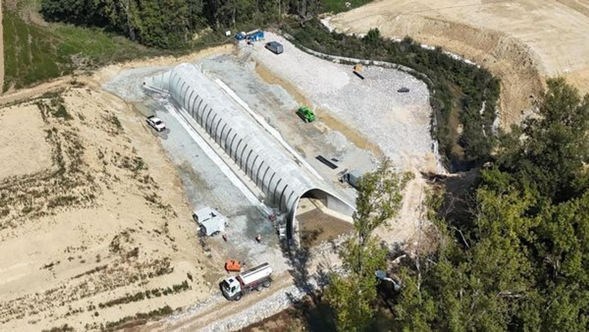 A Cambon-Lès-Lavaur, le concessionnaire ne pourra pas se cacher derrière la lutte qui fait rage pour justifier son retard ! Pour traverser le ruisseau d'Algans, qui se retrouverait sous des remblais de 10m de haut, l’A69 nécessite ici la construction d'un pont de 7 mètres de large sur 40 mètres de long. Mais dans ces lieux bucoliques défigurés par le chantier, NGE-Atosca s’est une nouvelle fois surpassé en signant ce qui est incontestablement sa plus belle œuvre à ce jour : c'est le Pont-Pont ! 
A première vue pourtant, tout semble prêt ! Une épaisse dalle de béton repose sur un profond enrochement censé drainer les eaux affleurantes de cette zone humide. Sur cette dalle, l'imposant pont voûté semble parfaitement terminé ! Il s'agit d'un ouvrage de rescindement du ruisseau d'Algans qui serait dévié pour passer sous ce pont. 
Mais à y regarder de plus près, les premiers coups de meuleuses au sol dévoilent l’improbable bévue d’Atosca ! Et pour cause, ce pont n’a tout simplement pas été construit au bon niveau. Il devrait se situer près d'un mètre plus profond pour permettre l'écoulement du cours d'eau...