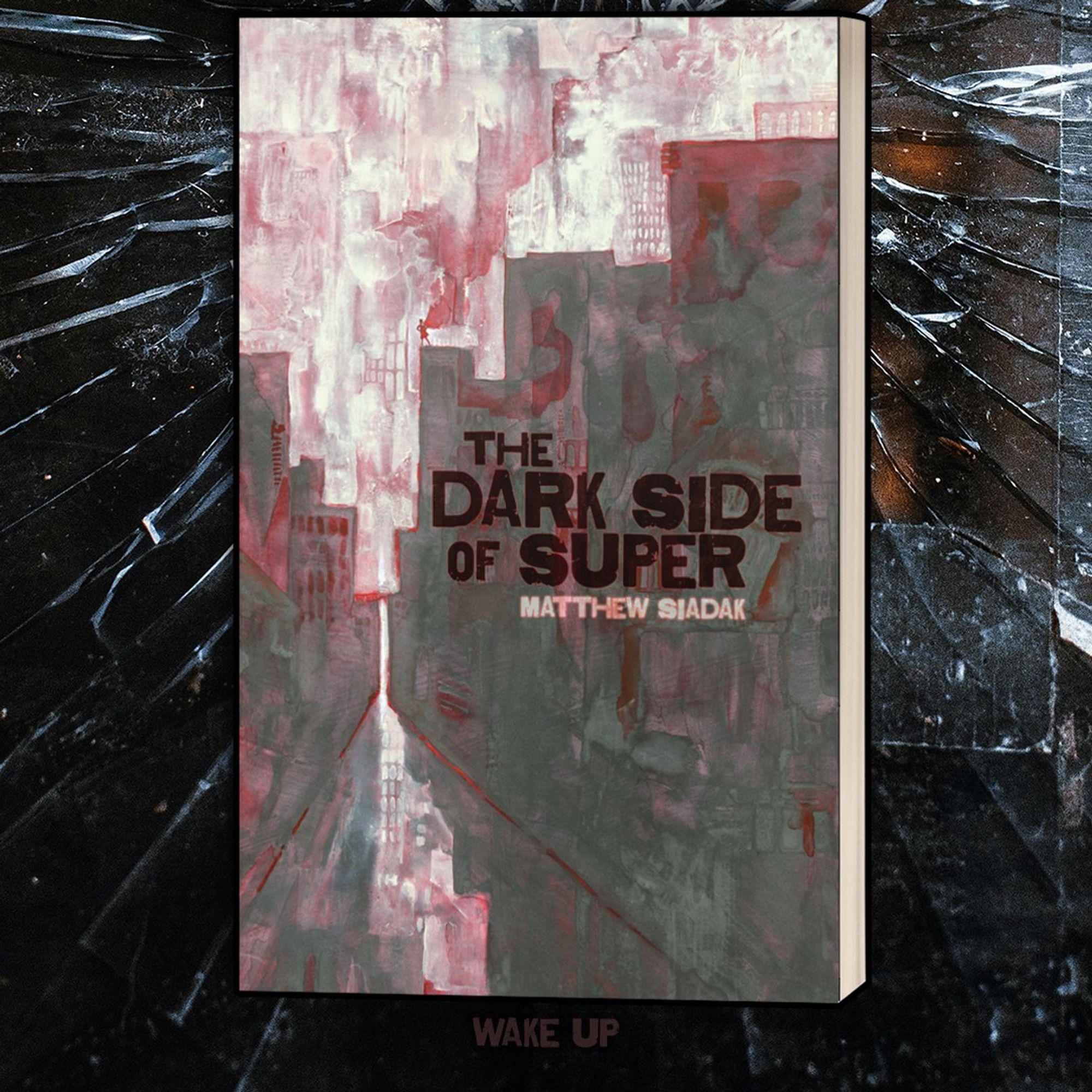 Image of a book, The dark Side of Super, on a spider-webbed broken glass bed. Near the bottom, the words "wake up" are hidden in the shadow of the book.