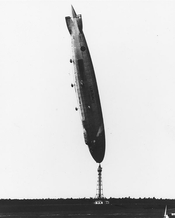 Extremely rigid airship USS Los Angeles at an angle unsuitable for pre-watershed TV. It's nearly vertical, with the bow still moored to its mast.