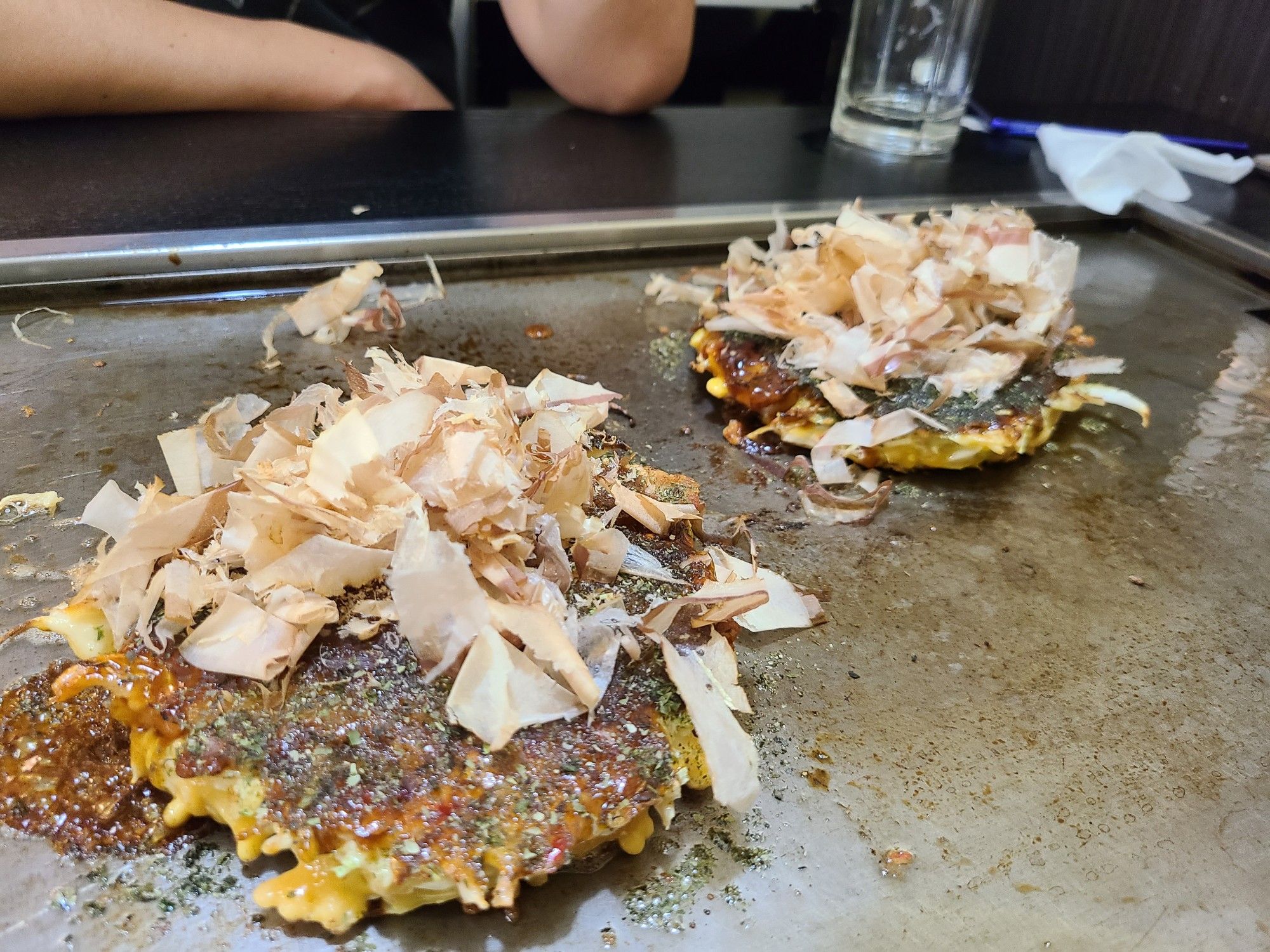 Two finished okonomiyaki with sauce and shaved bonito