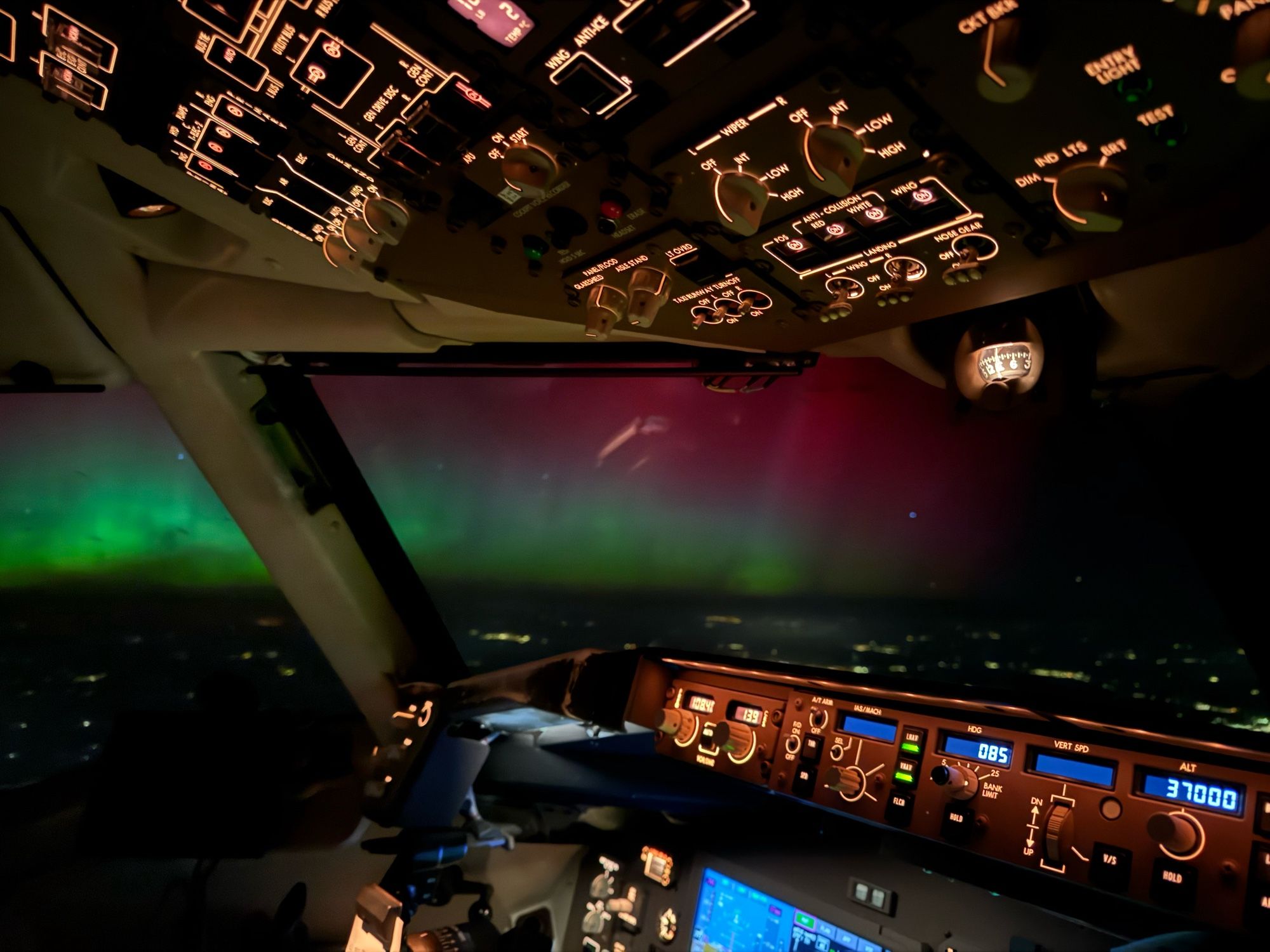 Green and red Aurora seen looking out across an airliner cockpit