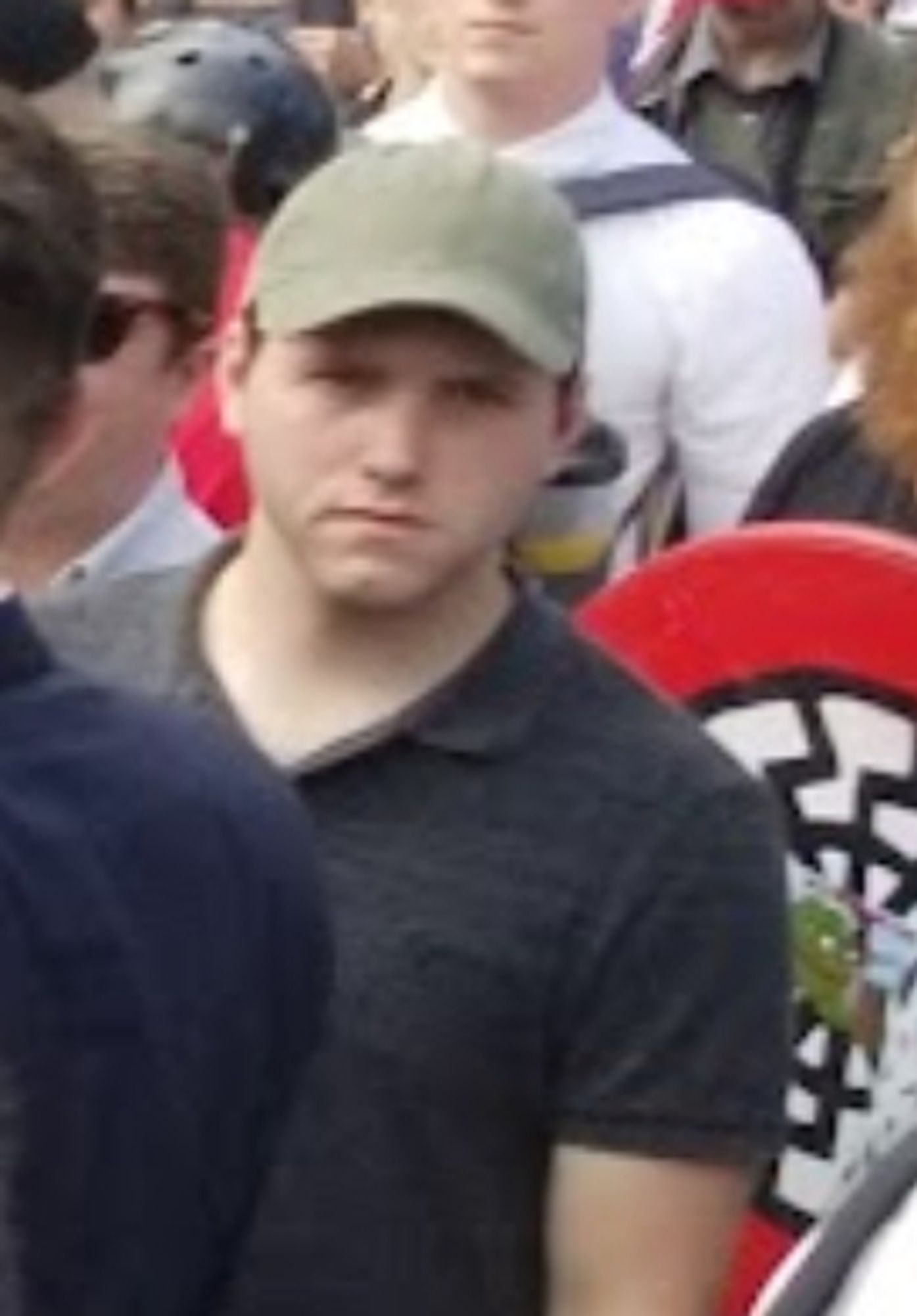 Logan Michael Smith at Unite the Right with a sonnenrad shield behind him.