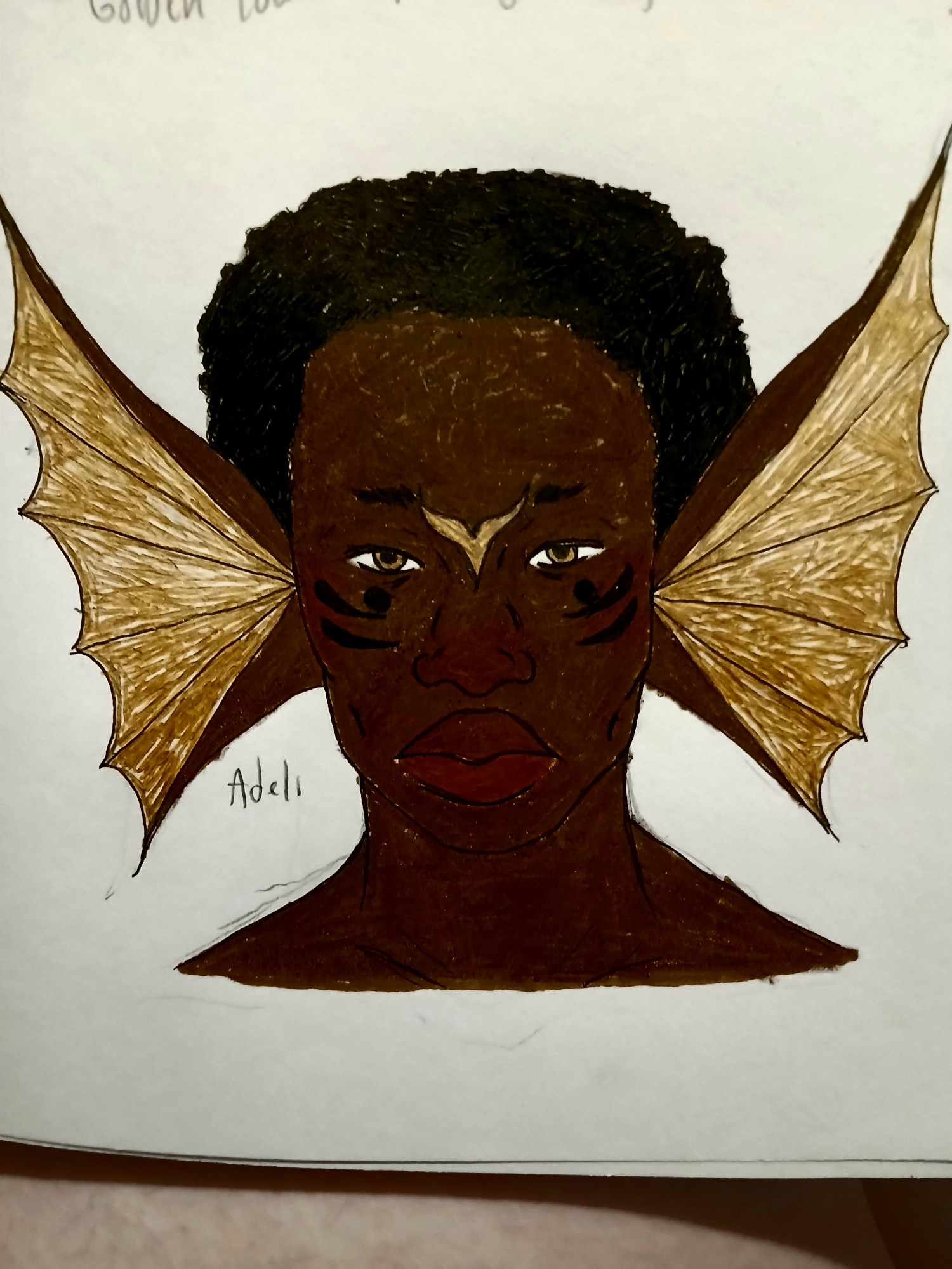 A merman with dark-skin that has a neutral undertone. The photo only shows him from the collarbone up. His ears are the same as described in the previous picture. He has big lips, the upper being a darker color than the lower one. He has a wide nose. He has a large black dot under both eyes and two black stripe under those. Between his eyes and above his nose bridge is the golden stylized 'v' symbol. He has sparse brows, epicathric folds, and gold irises. He has a thin face. He has a short black afro.