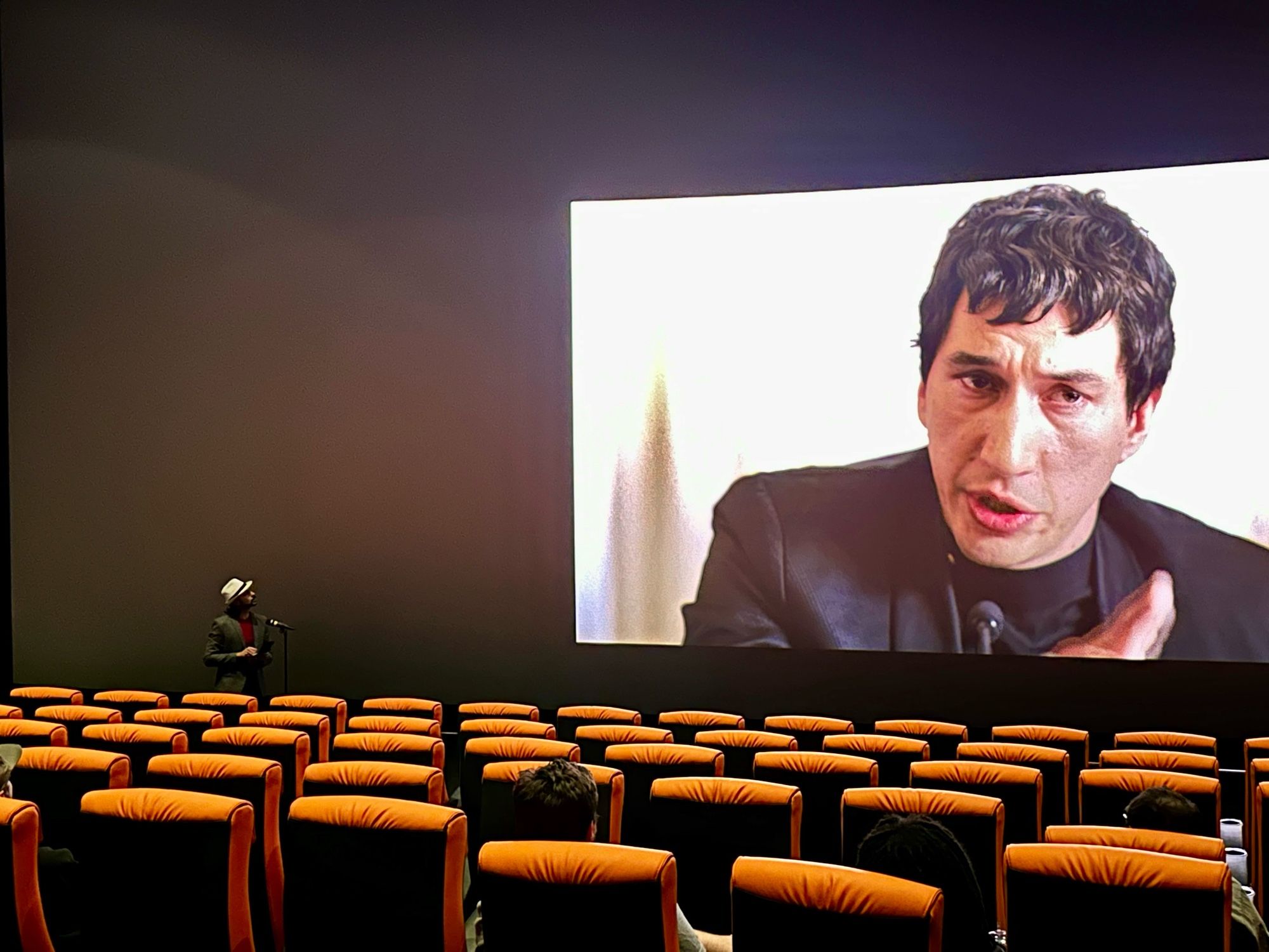 A brief moment from a screening of Francis Ford Coppola’s Megalopolis: The Ultimate Experience on opening weekend. Mid-movie, an actor dressed as a journalist in front of a microphone in the front row of the theater with the house lights briefly up asks questions of Cesar Catilina, who appears in a portion of the IMAX screen and responds to the question. A fusion of theatrical experiences, both proscenium and cinematic. An extraordinary achievement and milestone in the entertainment industry, unique to this film.