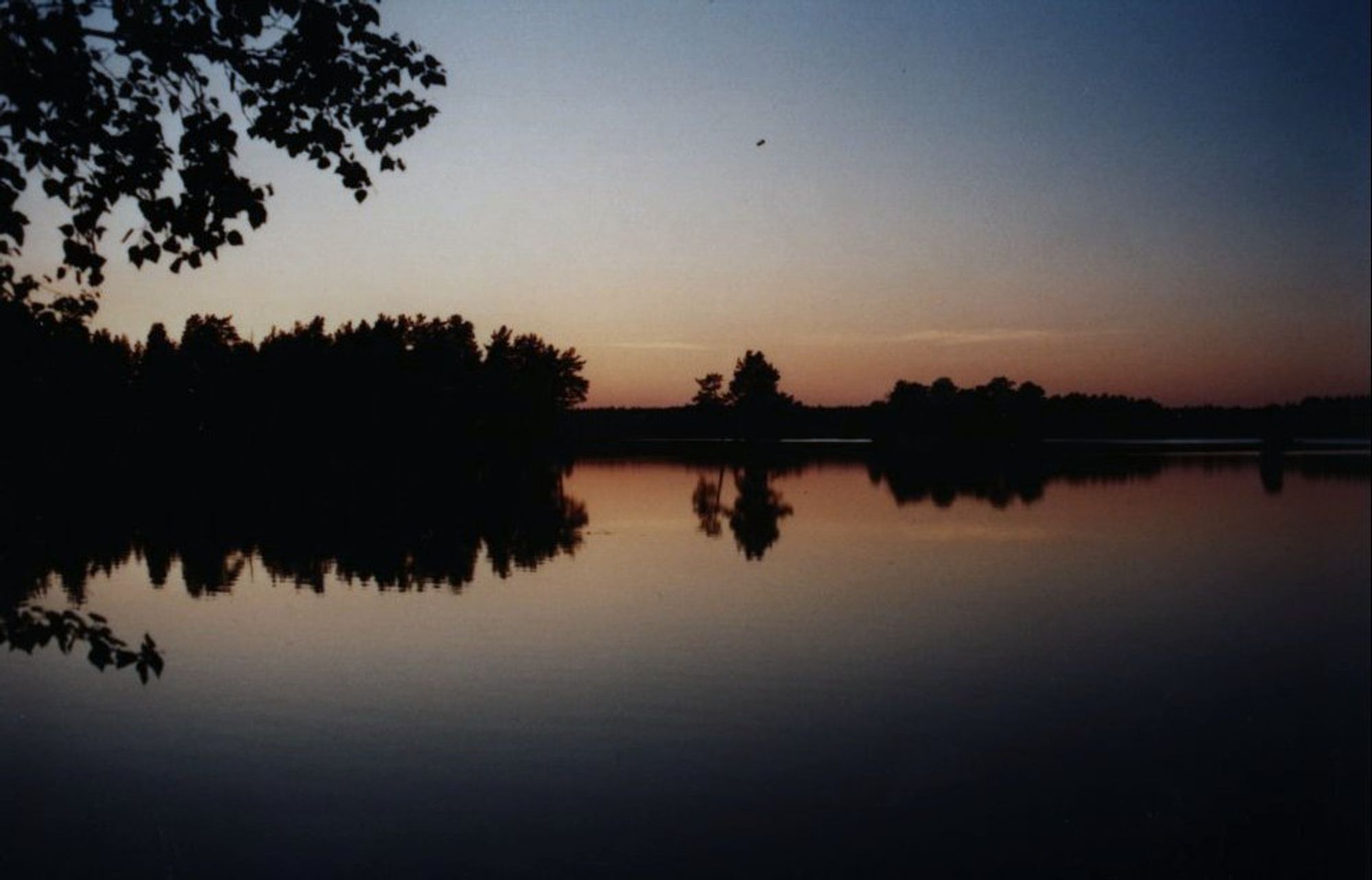 Ein spiegelglatter See während der stimmungsvollen Abenddämmerung in Schweden.