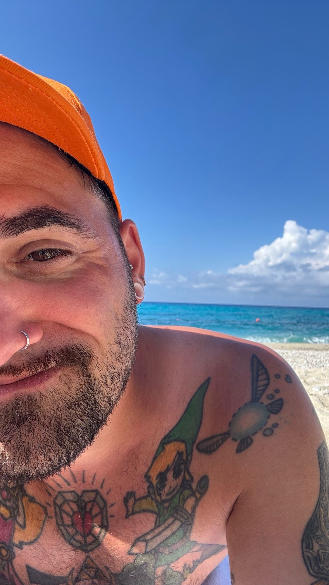 Mann mit basecap und tattoos liegt an Strand