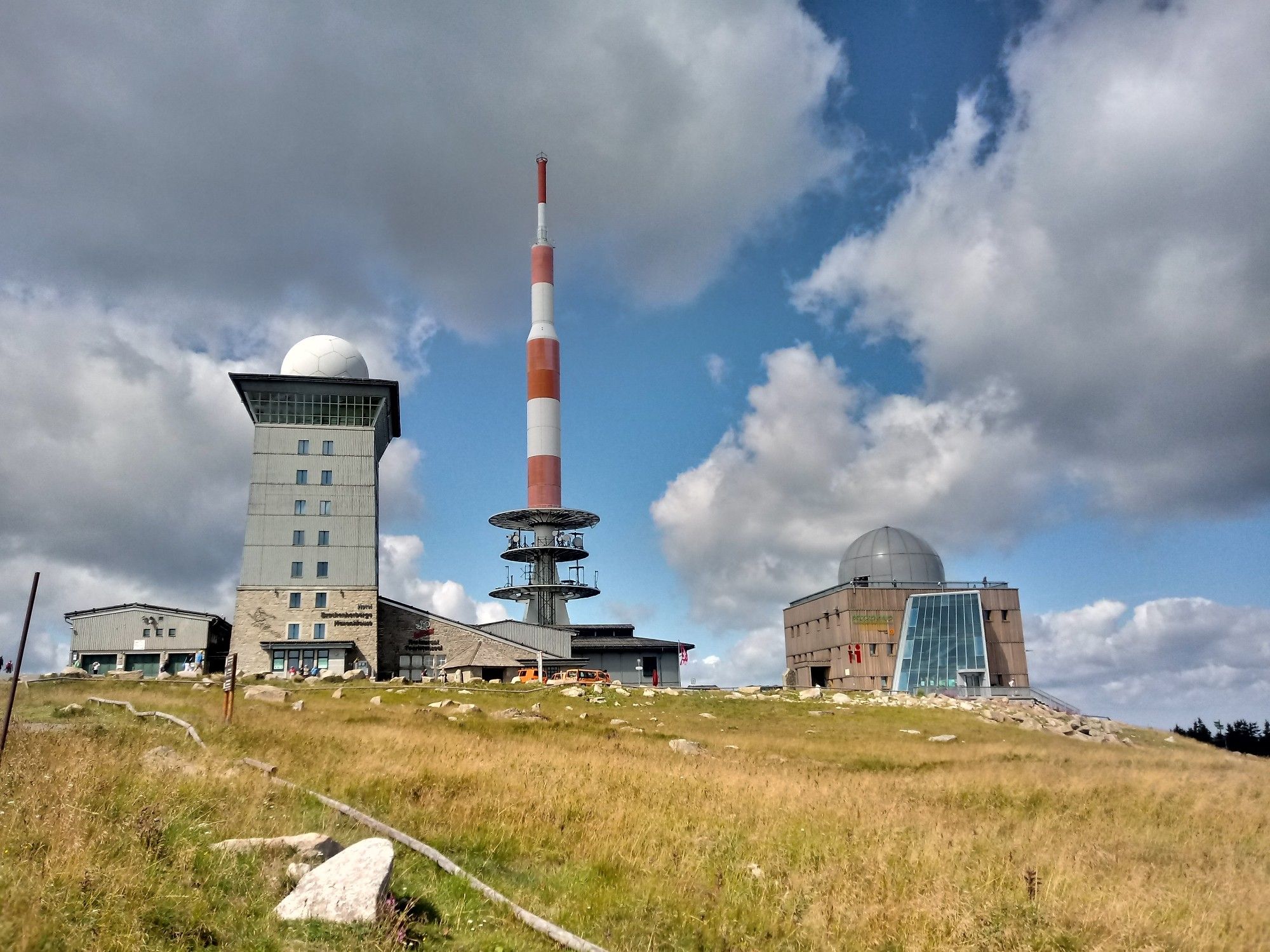 Der Brocken auf dessen Gipfel mehrere Gebäude stehen. Unter anderem, ein Sendemast ubd ein sieben Stockwerke quadratischer Turm.