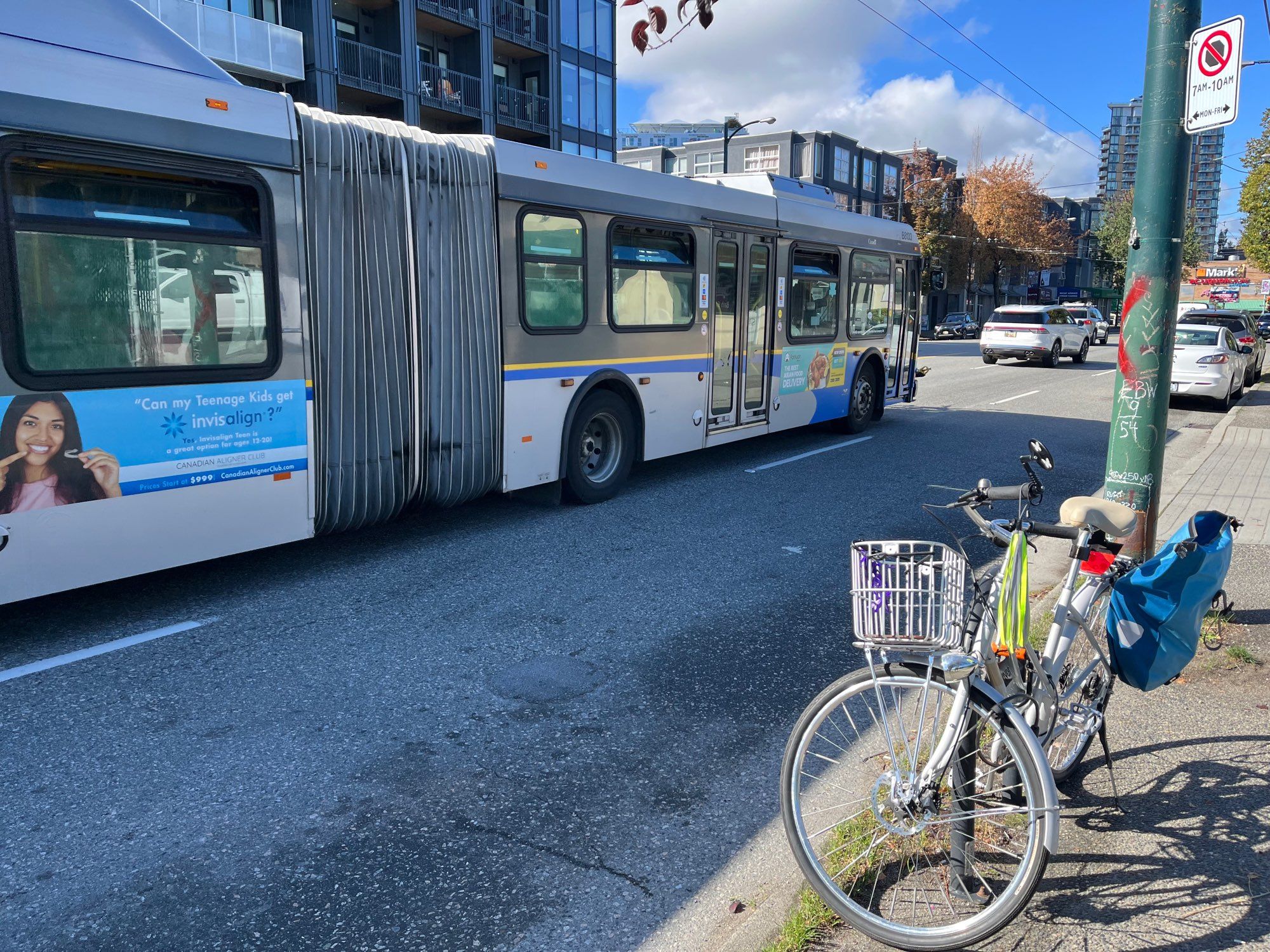 Photo of a bike parked at a bike rack in front of a bus driving past on Vancouver's Broadway.